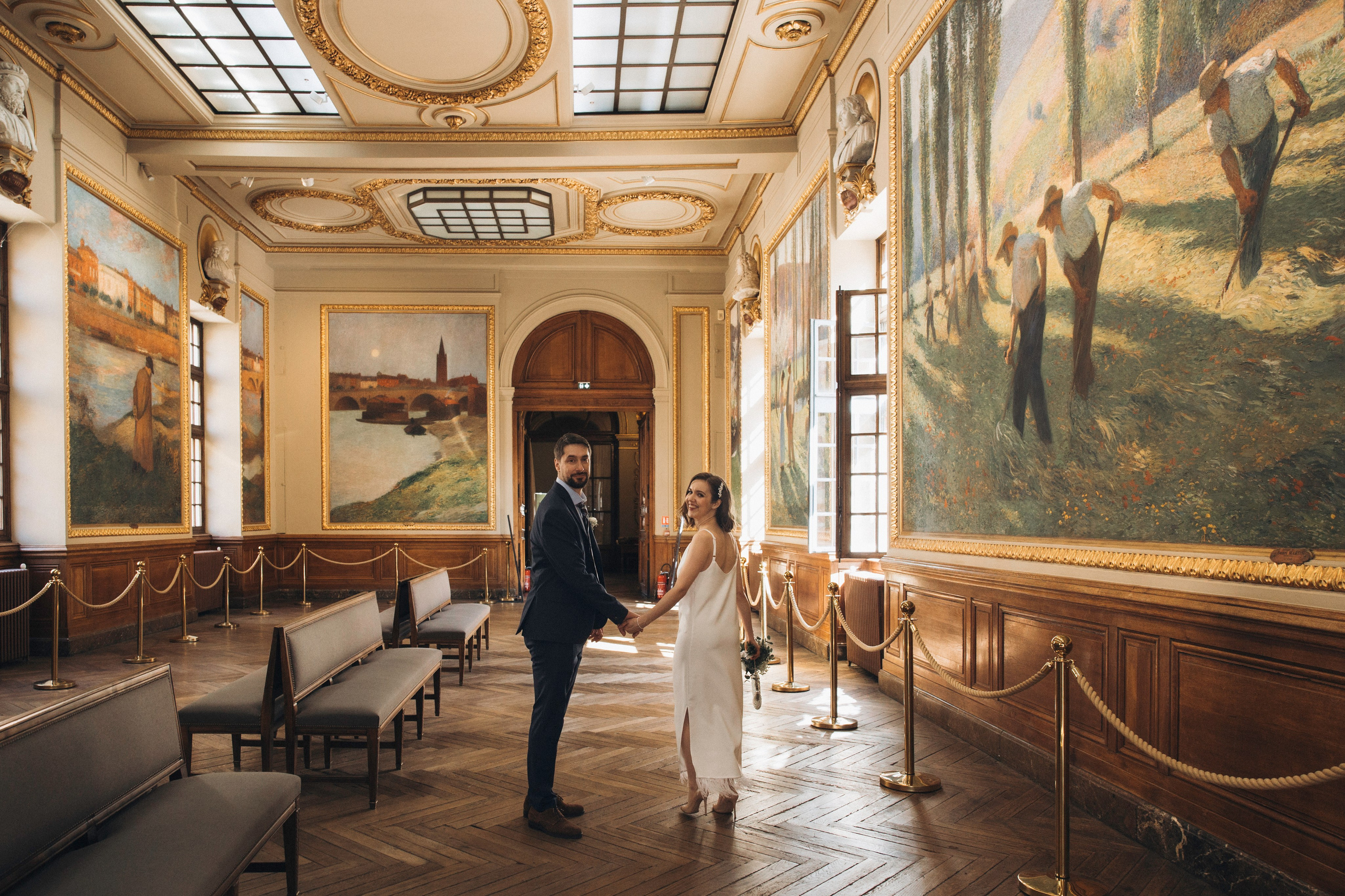Newlyweds hand in hand in the frescoed Salle des Illustres of the Capitole, Toulouse