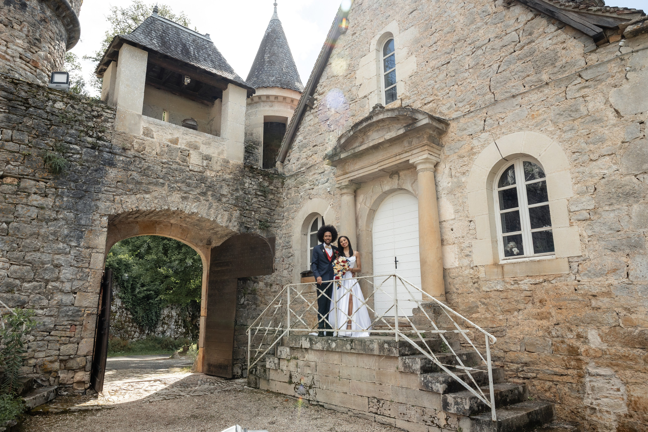 Les mariés s'enlacent devant un château en pierre dans leSud-Ouest de la France lors d'un mariage de destination.Photographie de mariage documentaire par Eugénie Smirnova.