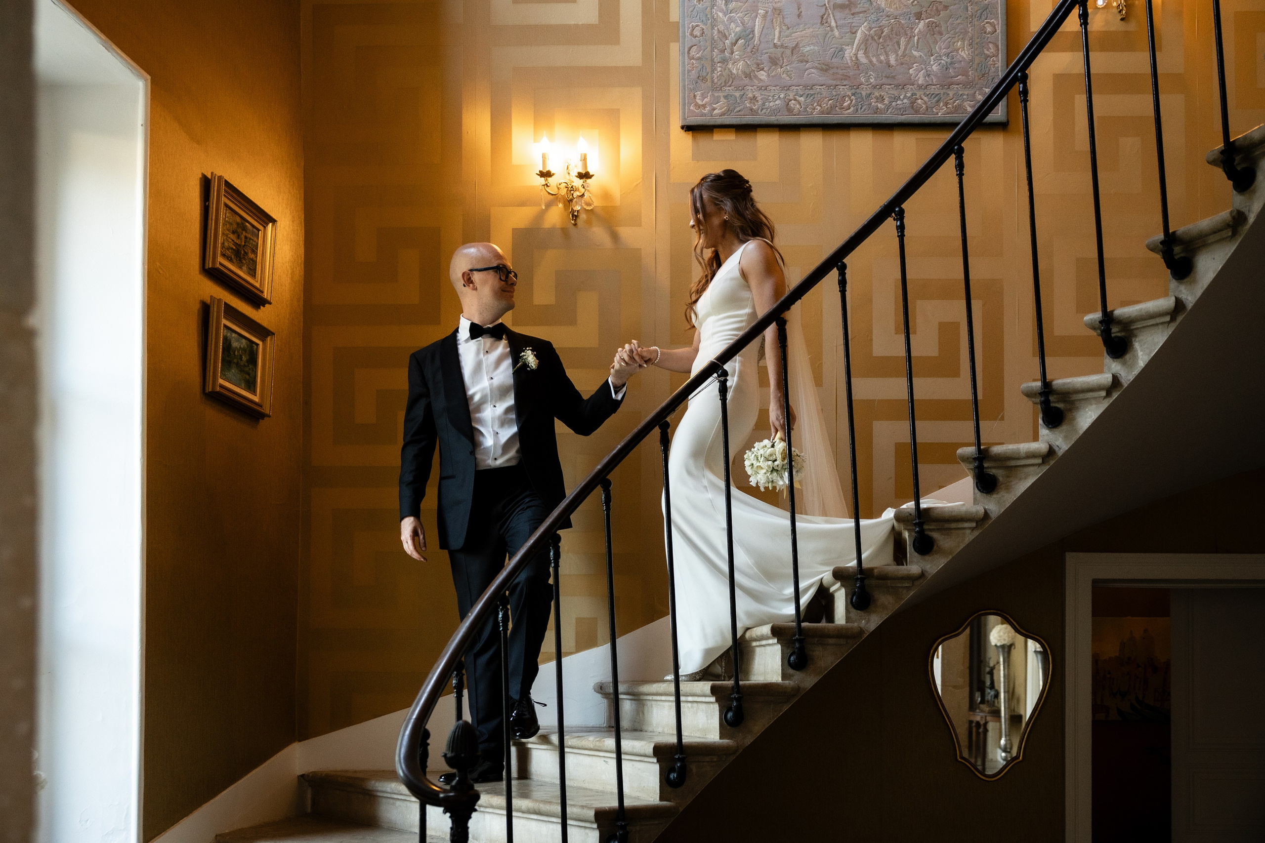Groom leading the bride down the curved staircase at Château de la Borderie