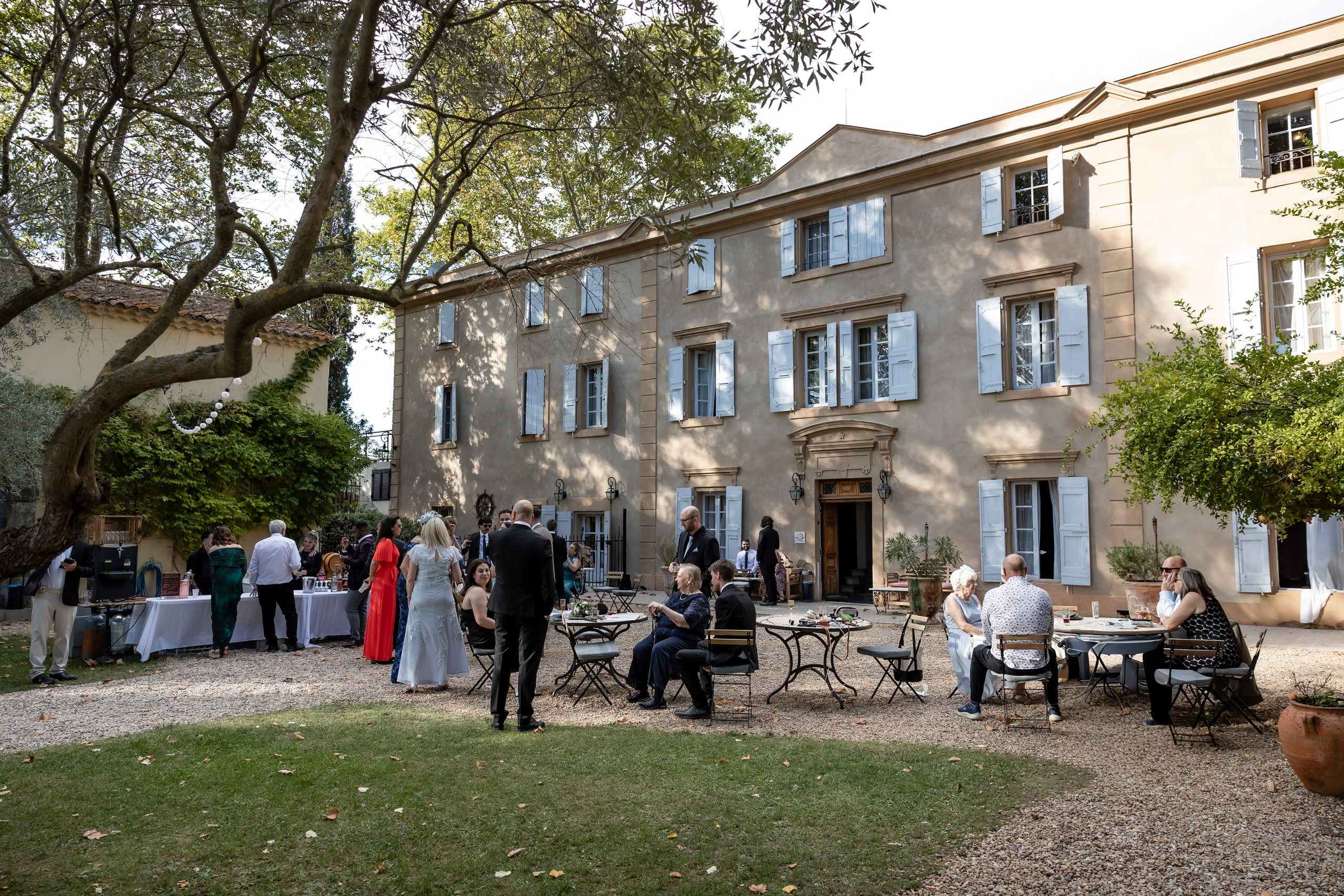 Invités profitant du cocktail dans la cour du Château Rieutort lors d’un mariage intimiste d’automne dans le Sud-Ouest de la FranceCérémonie de mariage en plein air sous les platanes centenaires au Château Rieutort, mariage de destination en FrancePièces cocktail de la gastronomie française servies lors du vin d’honneur au Château RieutortMariée souriante et émue pendant la cérémonie en extérieur au Château Rieutort, mariage d’automne dans le Sud de la FranceLes mariés marchant main dans la main sous les arbres du domaine du Château Rieutort après la cérémoniePortrait du couple et de leurs proches devant les grilles du Château Rieutort, mariage de destination dans le Sud de la FranceLa mariée entourée de ses demoiselles d’honneur en robes bordeaux au Château Rieutort, mariage d’automne en FranceLes jeunes mariés se promenant dans les jardins du Château Rieutort à la lumière dorée de l’automnePortrait romantique des mariés au Château Rieutort, entourés de cyprès, mariage de destination en FranceLa mariée se préparant à l’intérieur du Château Rieutort, enfilant ses chaussures avant la cérémonie