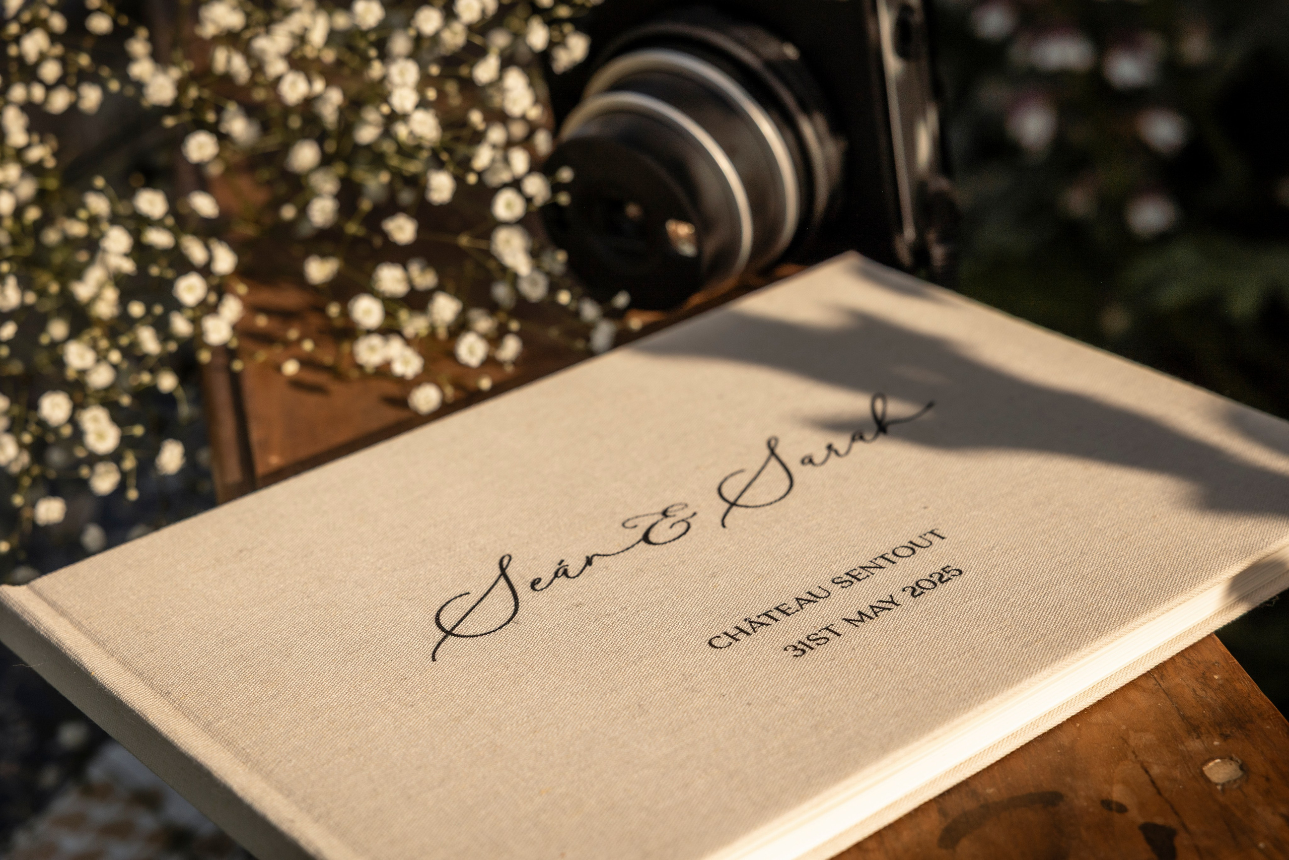 Elegant wedding guest book with the names Sean and Sarah photographed in warm golden light at Château Sentout wedding in France.