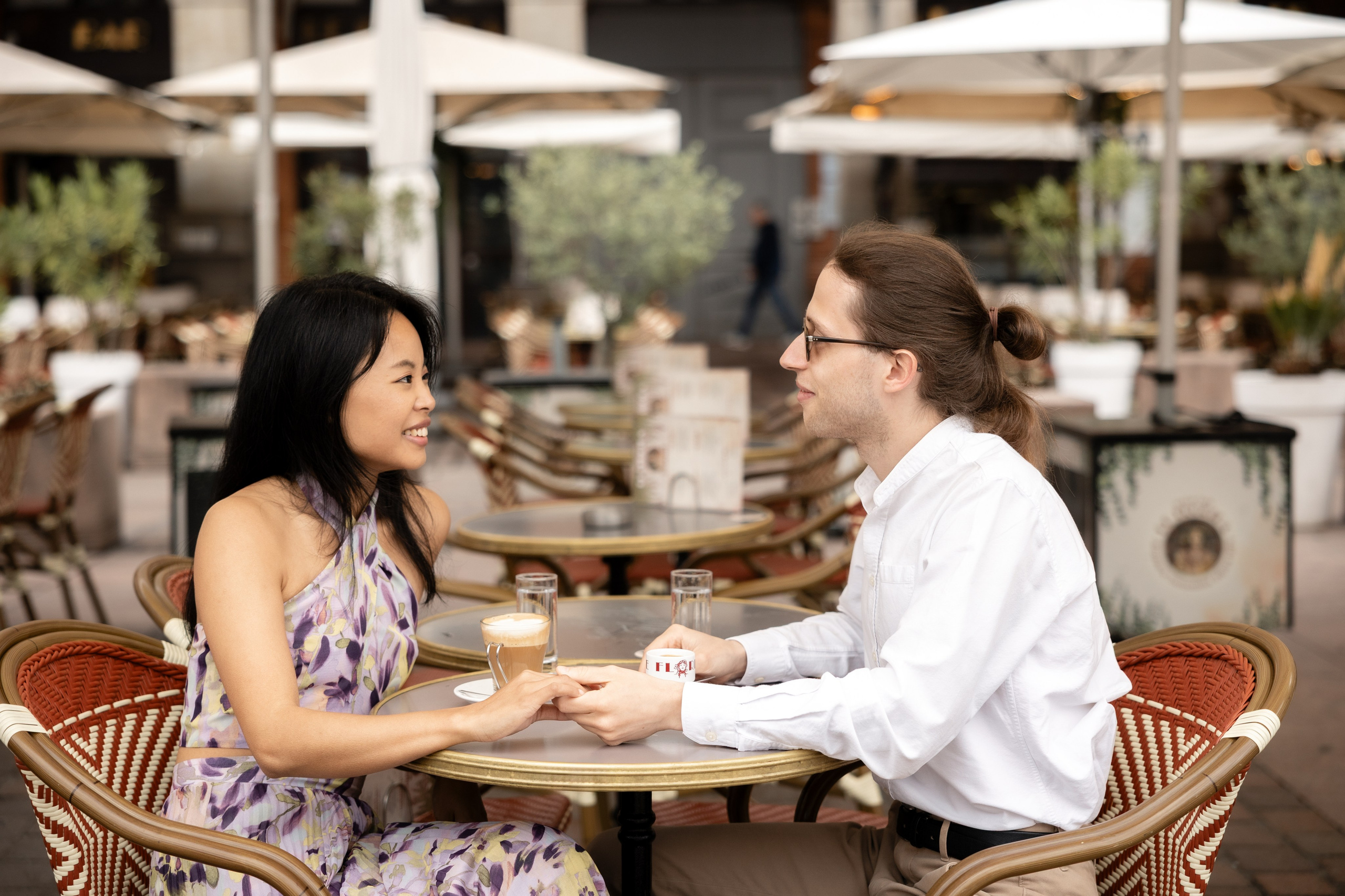 Couple holding hands over coffee at a café terrace in Toulouse