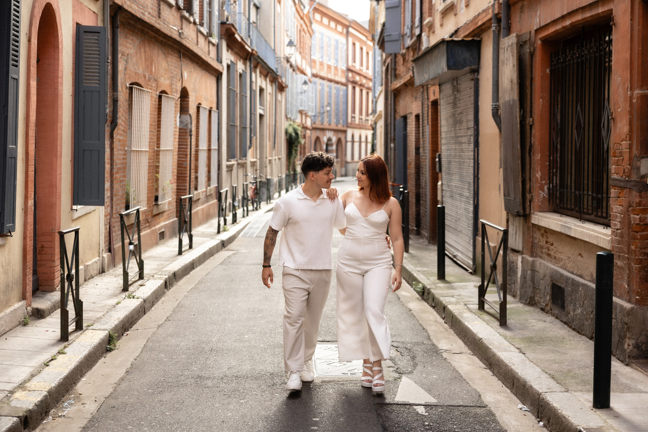 Couple walking down the narrow brick Rue du Taur in Toulouse