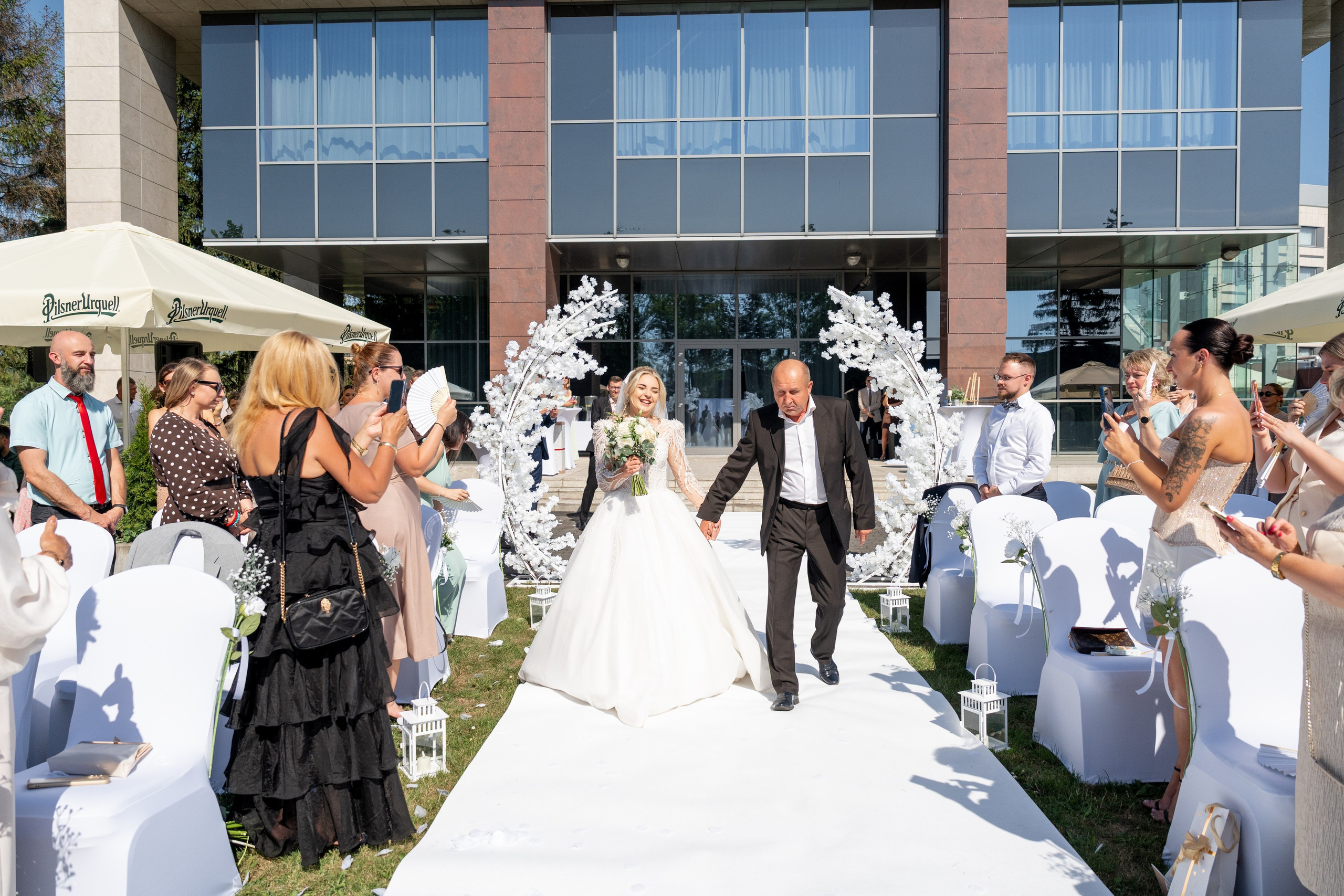 Panna Młoda idąca z tatą podczas plenerowej ceremonii ślubnej