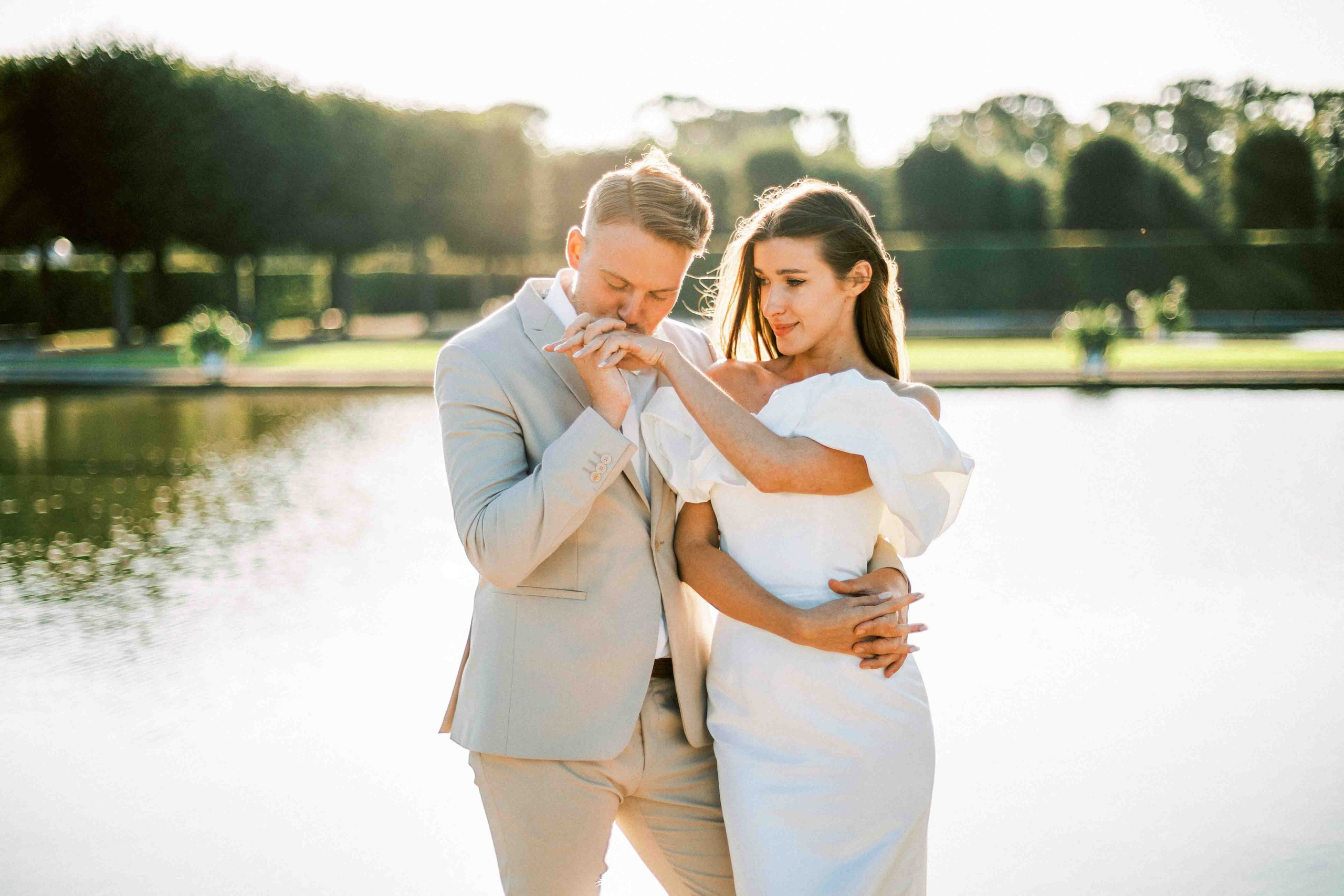pärchen zusammen am wassser während eines fotoshooting nach der hochzeit bräutigam küsst hand der braut
