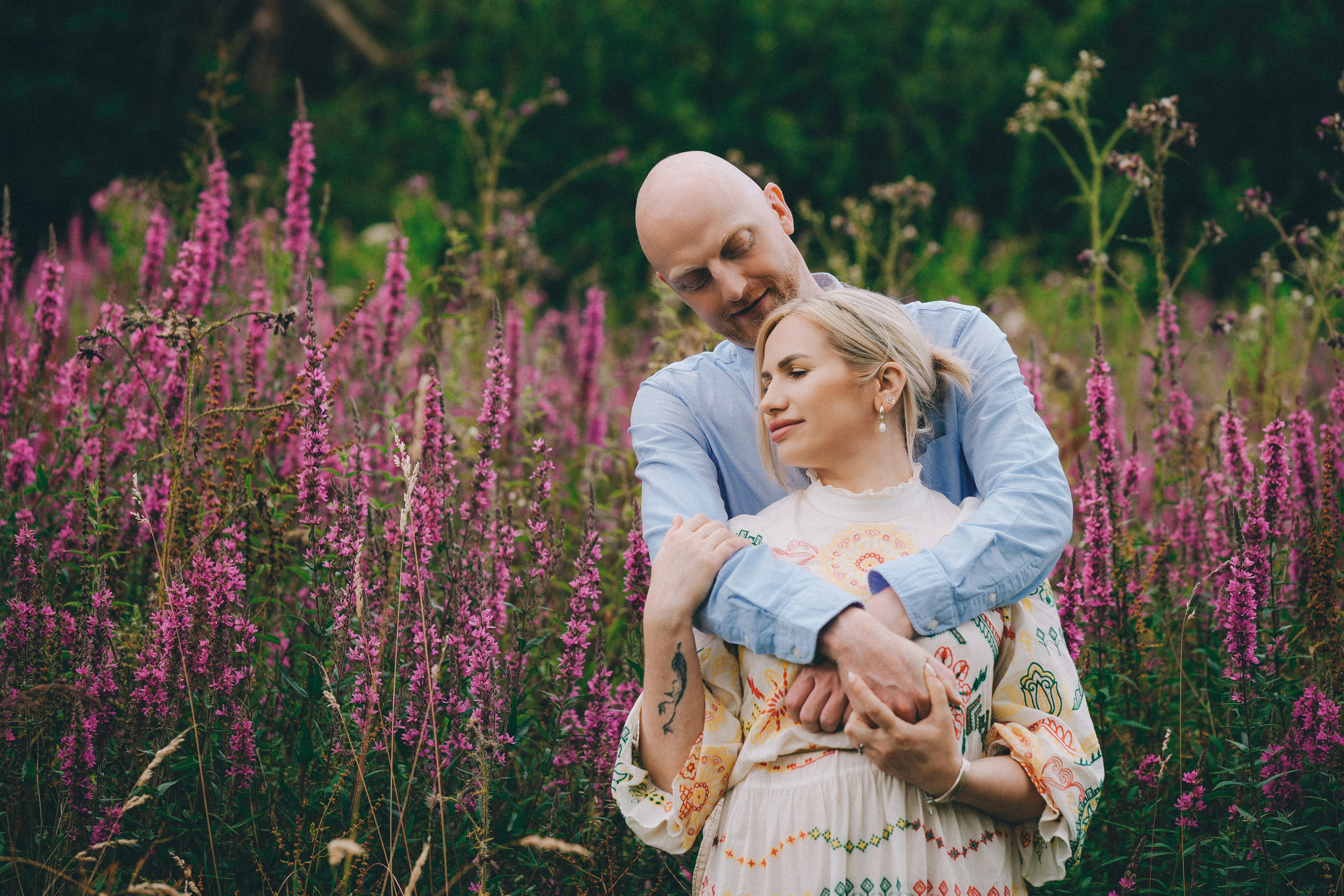 Man holding women in colourful wildflowers in Bourton countryside, emotional lifestyle family photograph