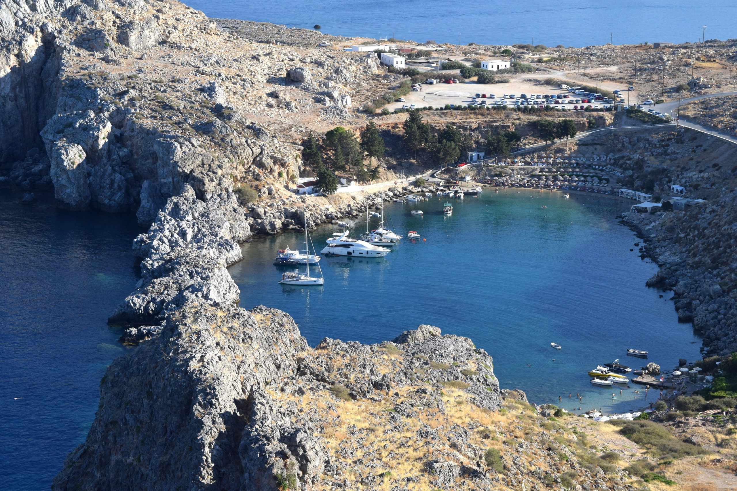Luftbild von Lindos, Rhodos: St. Paul's Bay mit Yachten im türkisfarbenen Wasser. Beliebte Hochzeits- und Urlaubsdestination in Griechenland mit felsiger Küste, kleinem Strand und Bootshafen.