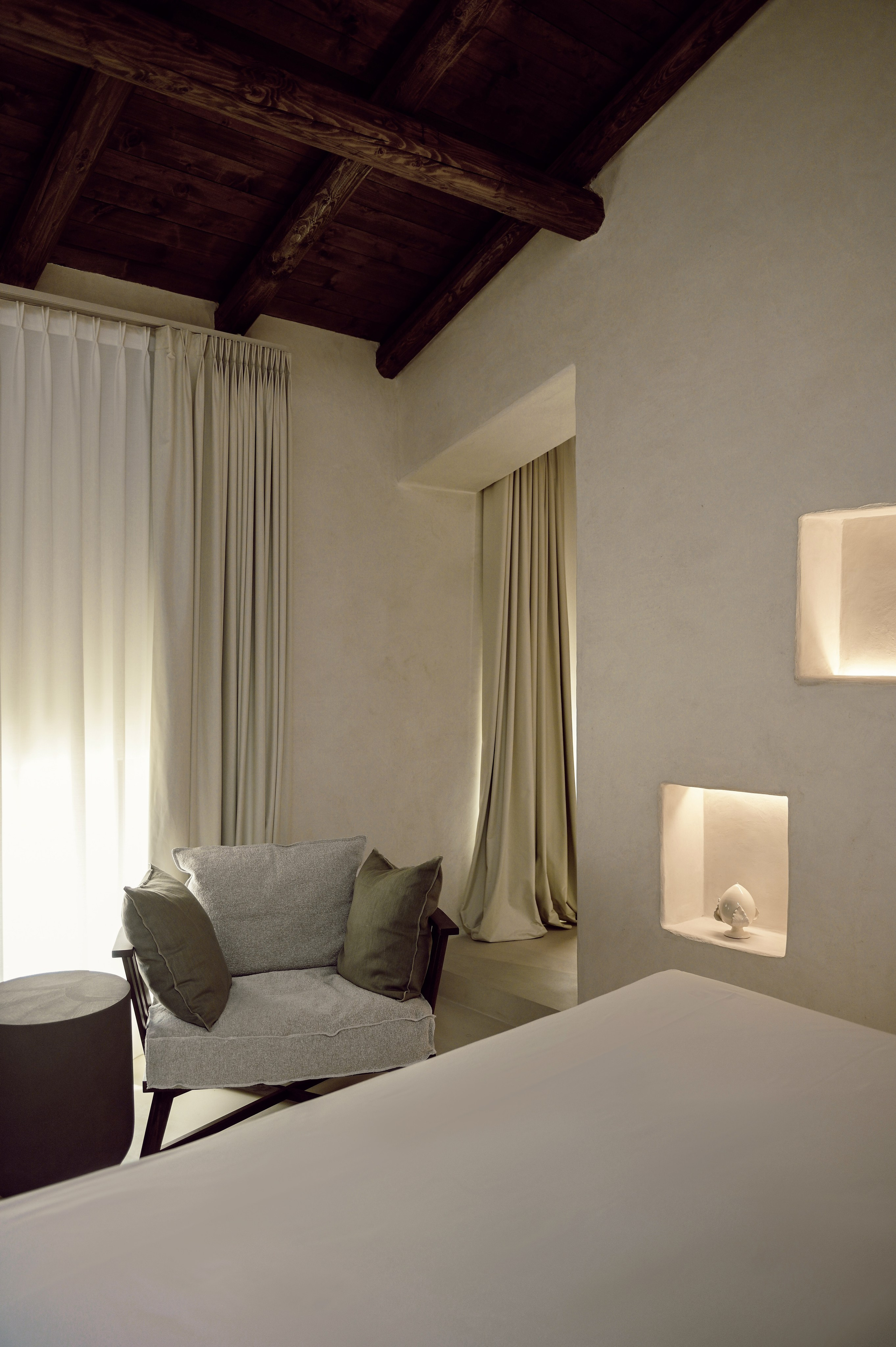 Cozy bedroom corner with linen curtains, soft lighting and neutral tones in a boutique interior in Puglia, Italy