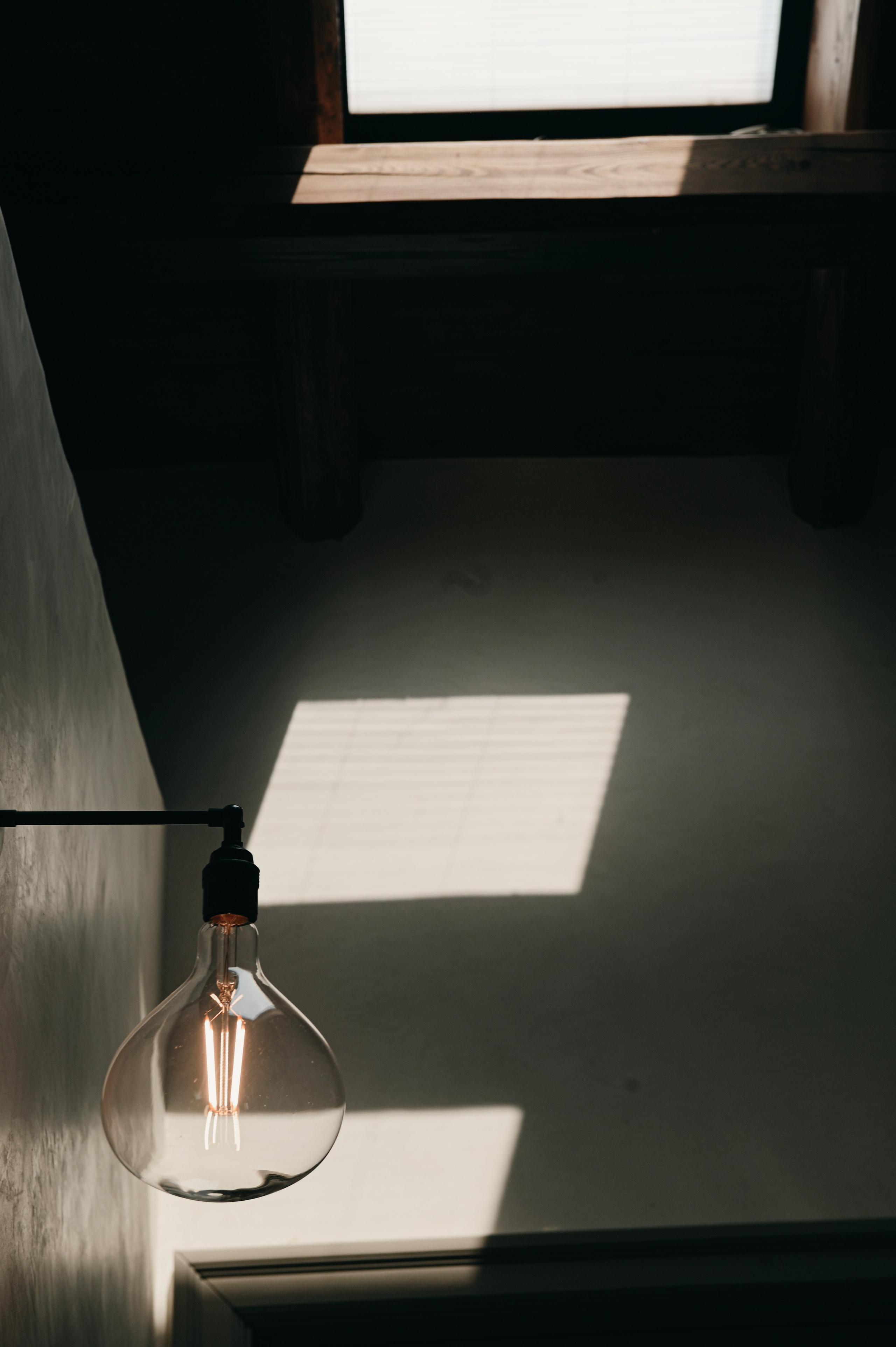 Interior photography detail with vintage wall lamp and natural light shadows in a rustic boutique home in Puglia.