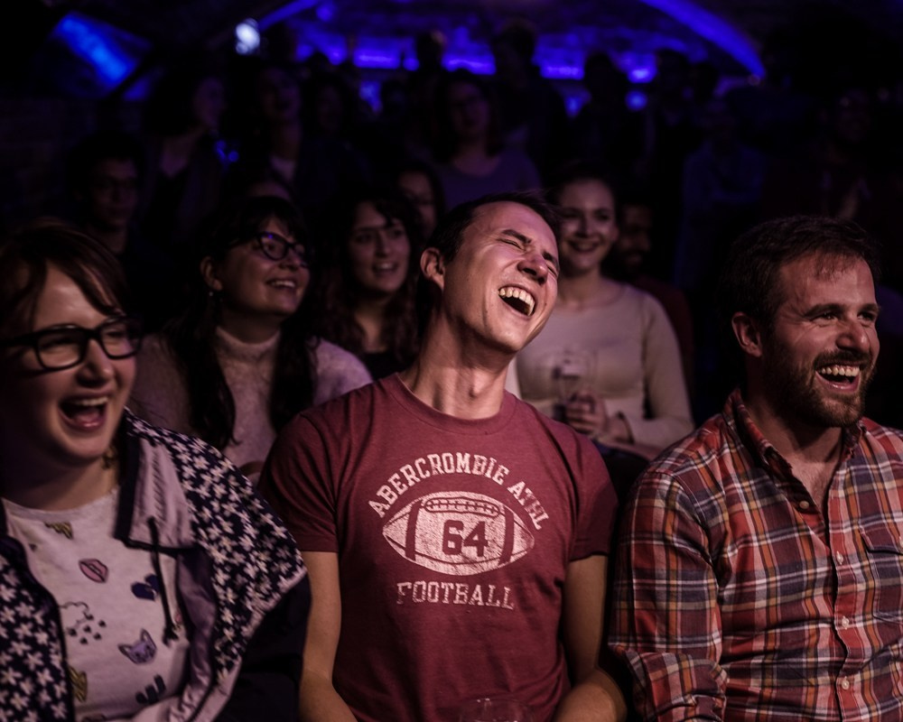 Event Photography: comedy night crowd featuring a man bursting in laughter in the middle.