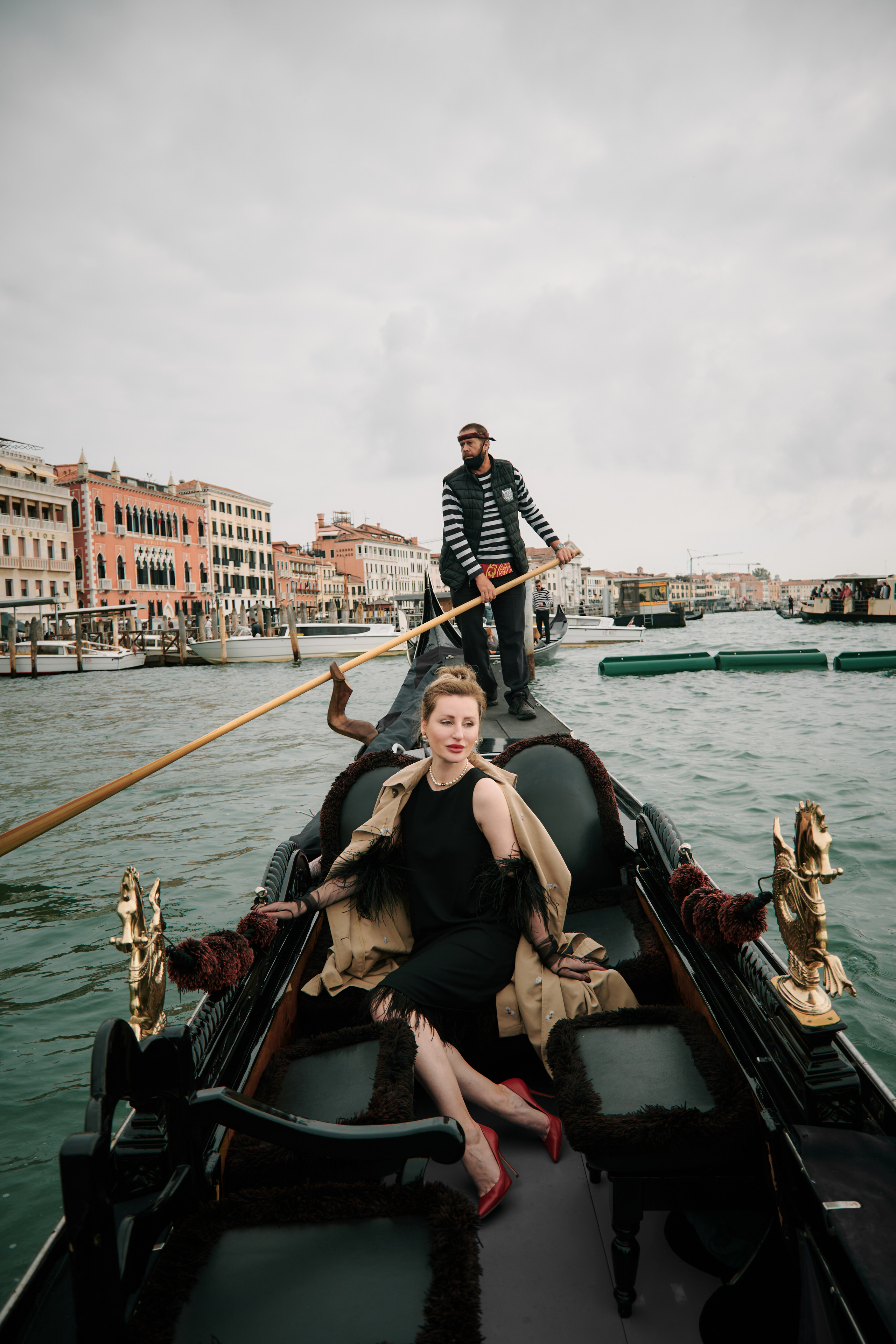 A heartwarming portrait of a woman on gondola ride near Sant Mark's square in Venice. The iconic San Marco square serves as the perfect backdrop, with its stunning architecture adding to the charm of the picture. Gondolier and gondola, Italy. girl in black. Fashion blogger shoot Venice. Portrait and Fashion Photographer in Venice, Italy. Instagram Photos with lifestyle photographer