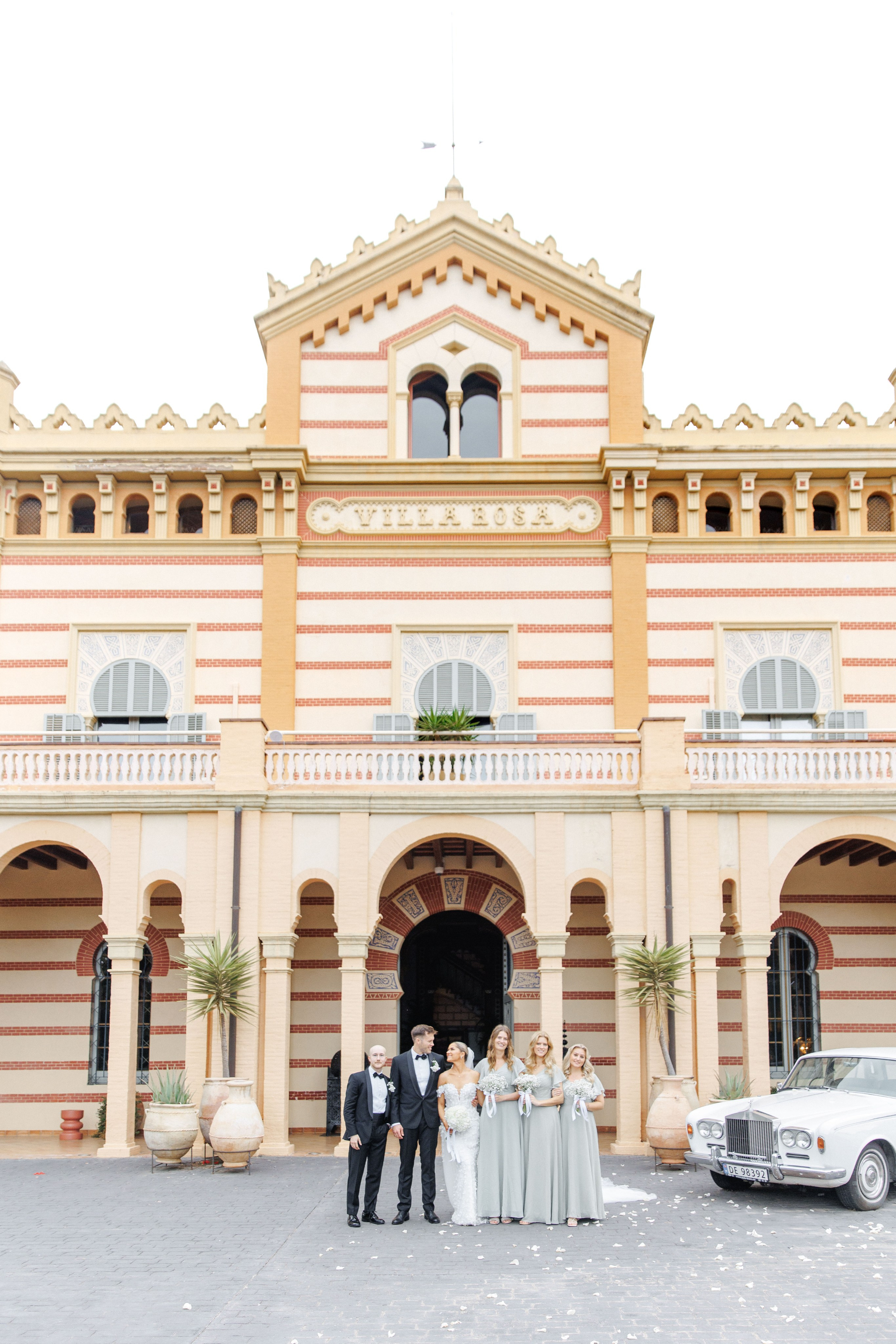 Groom and bride surrounded by friends in front of the destination wedding venue in Spain 