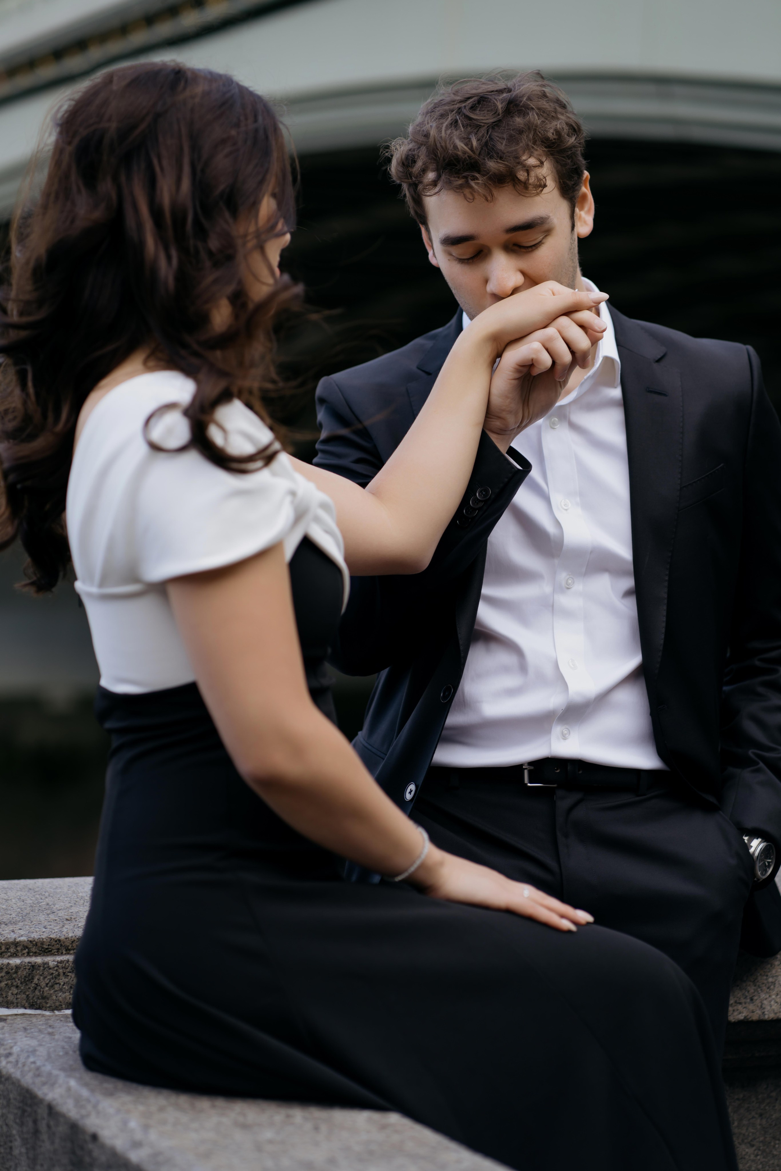 Stylish couple sitting near Westminster during London photoshoot in black evening outfits.