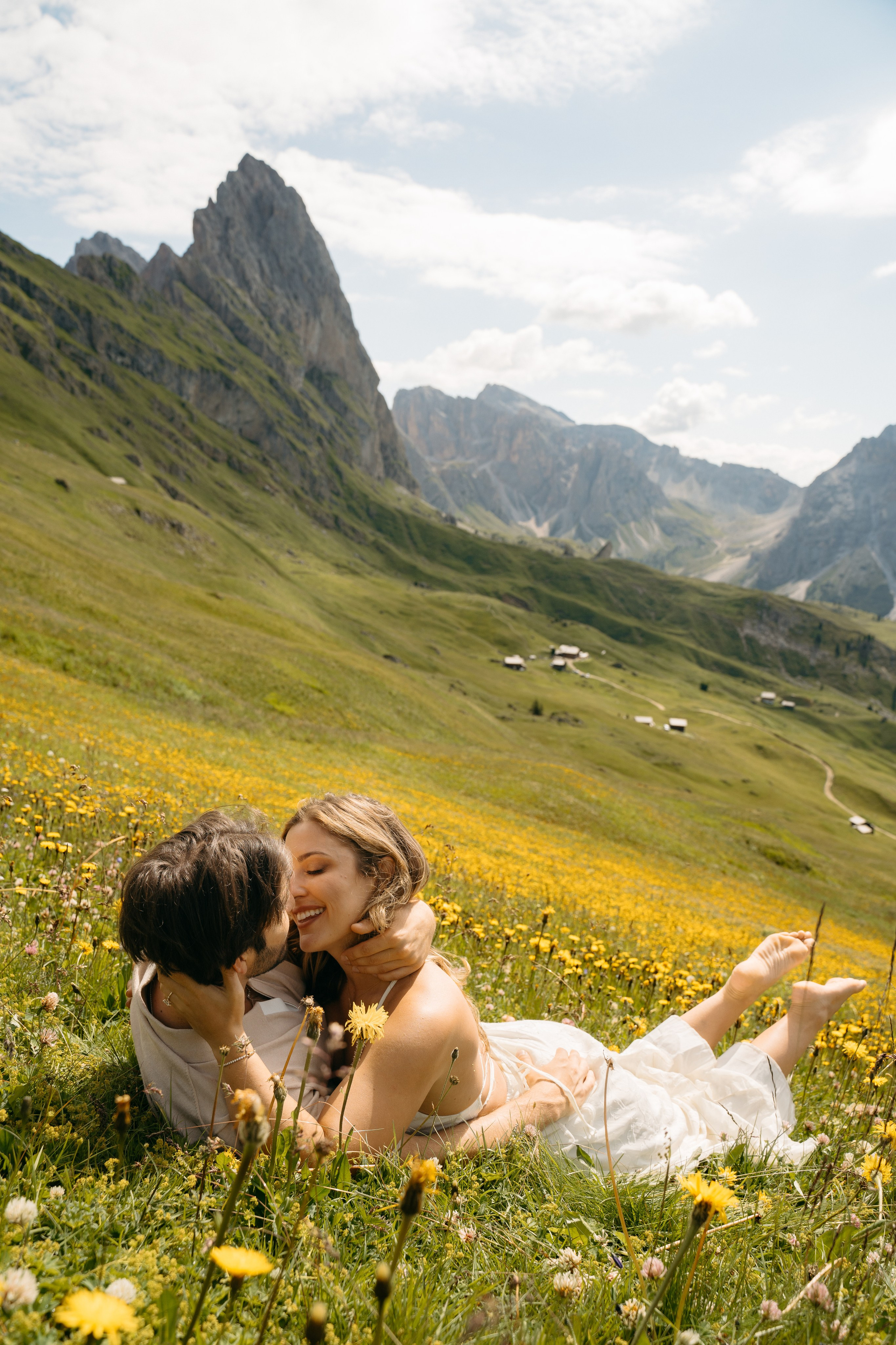 Couple laying in alpine meadow after Dolomites proposal, cinematic engagement photography in the mountains