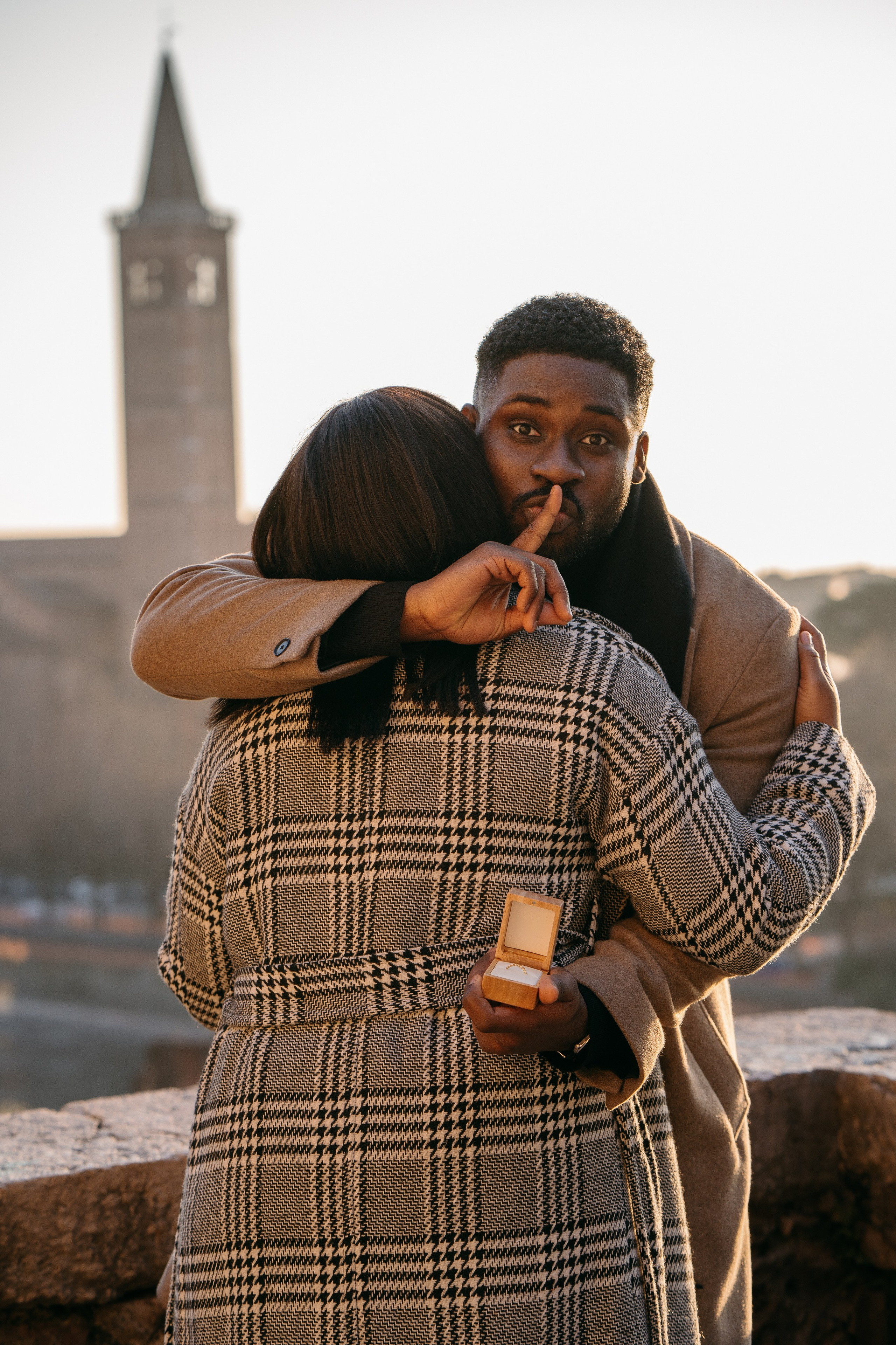 Couple embracing after a surprise marriage proposal in Verona at sunset.