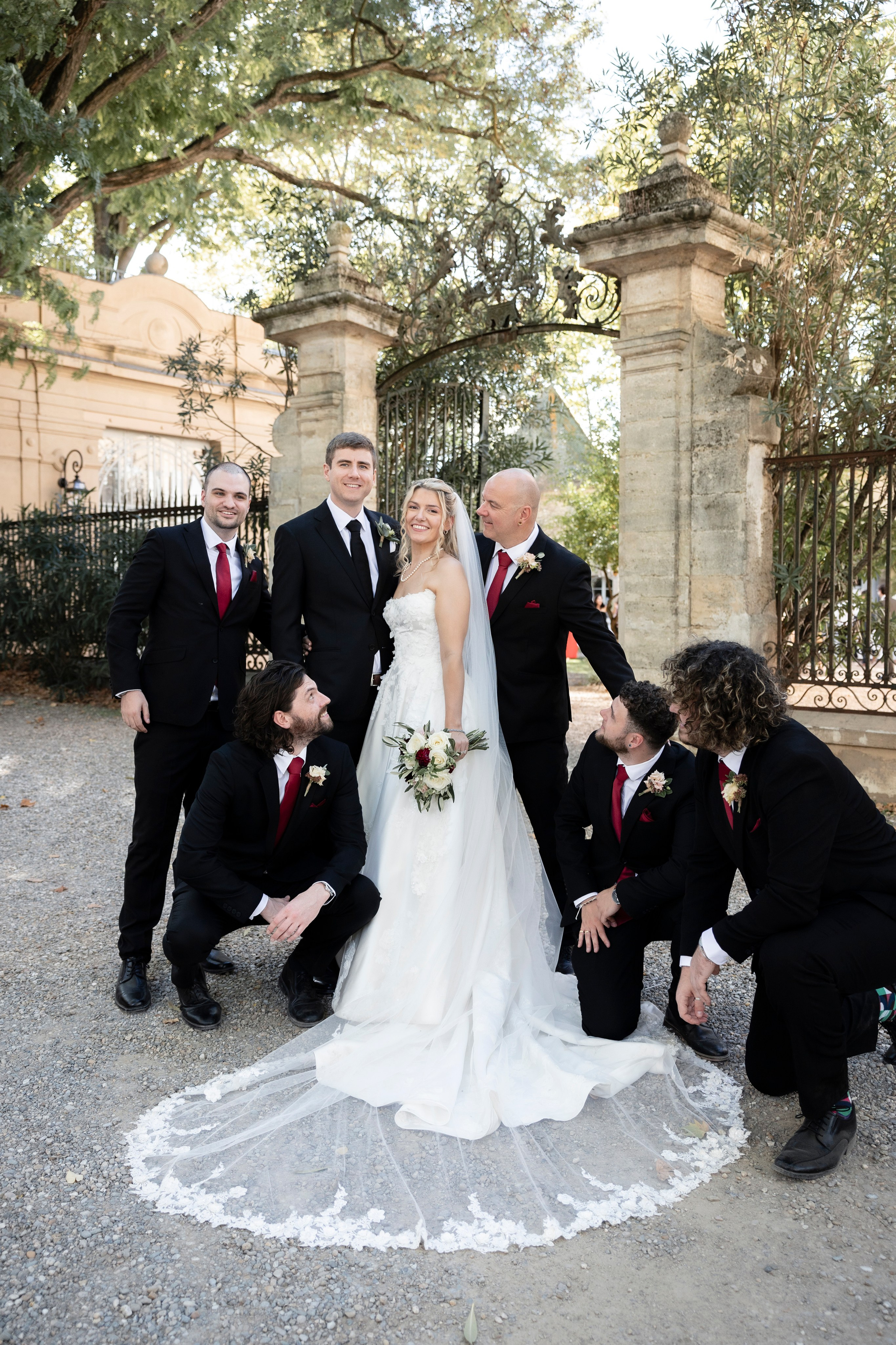 Portrait du couple et de leurs proches devant les grilles du Château Rieutort, mariage de destination dans le Sud de la France