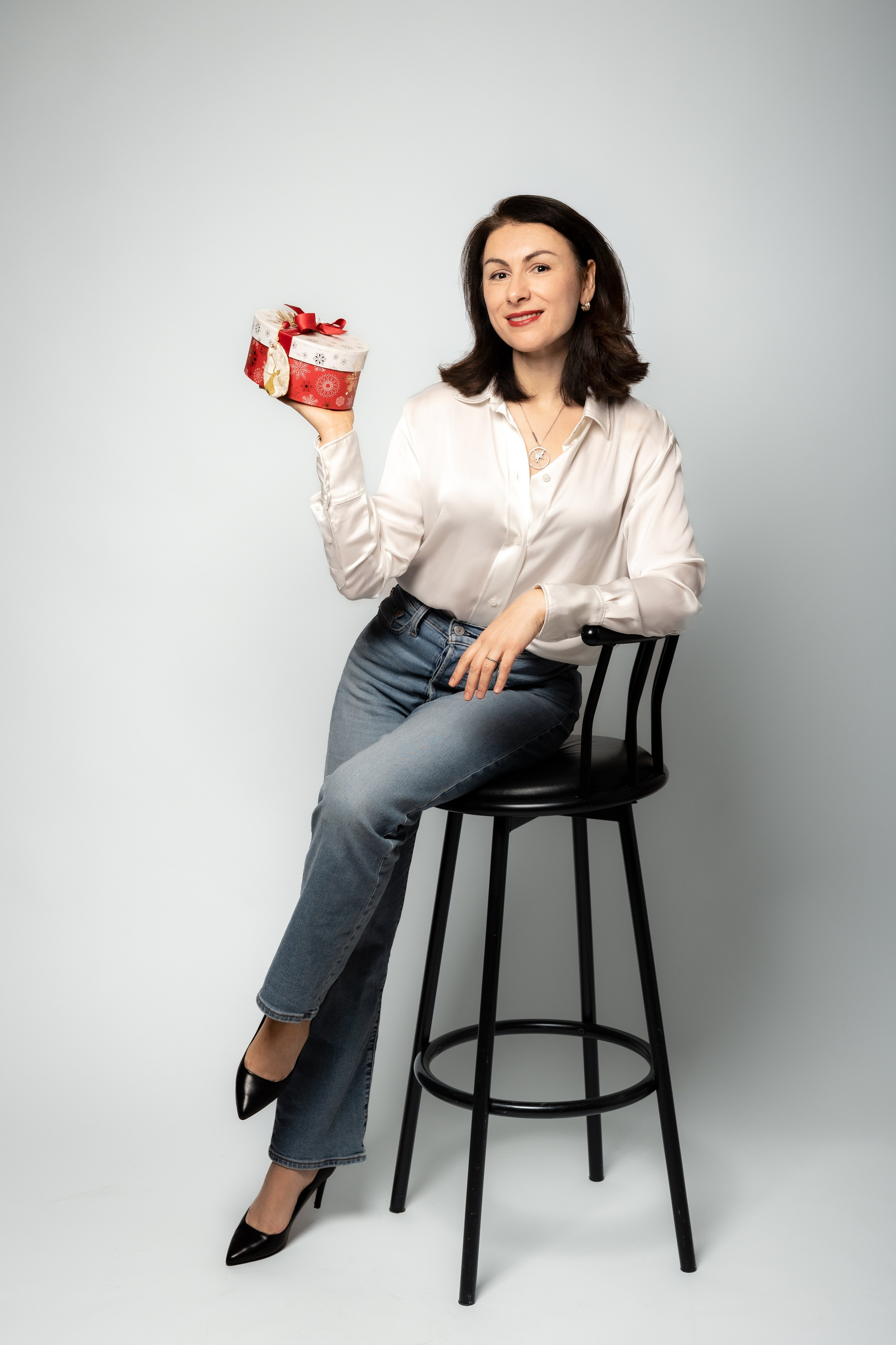 Portrait en studio d’une femme tenant une boîte cadeau de Noël pour une promotion photo.
