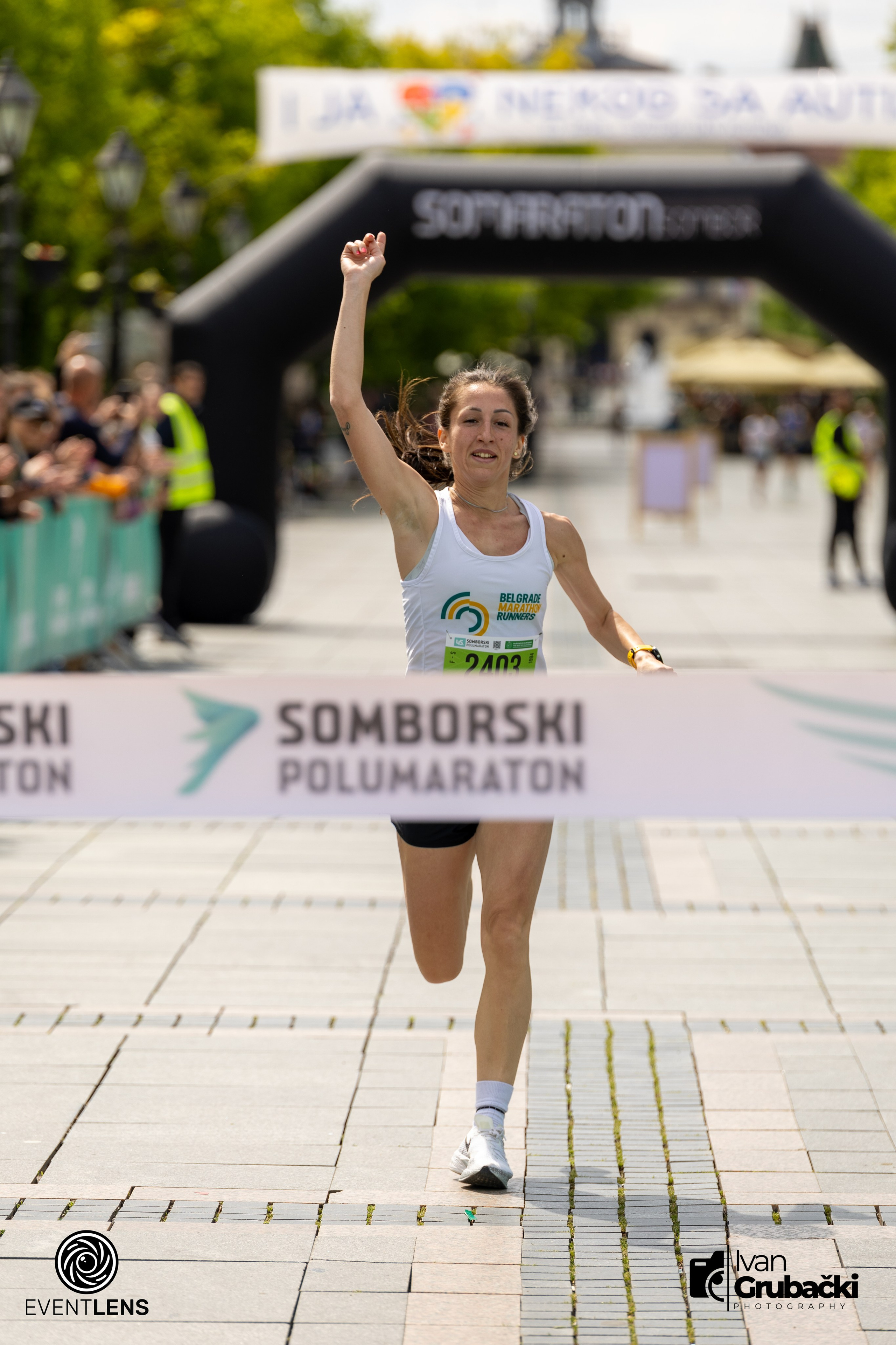 Ženska trkačica u finišu Somborskog polumaratona – prolazak kroz cilj uz publiku i vremenski sat. Grad Sombor