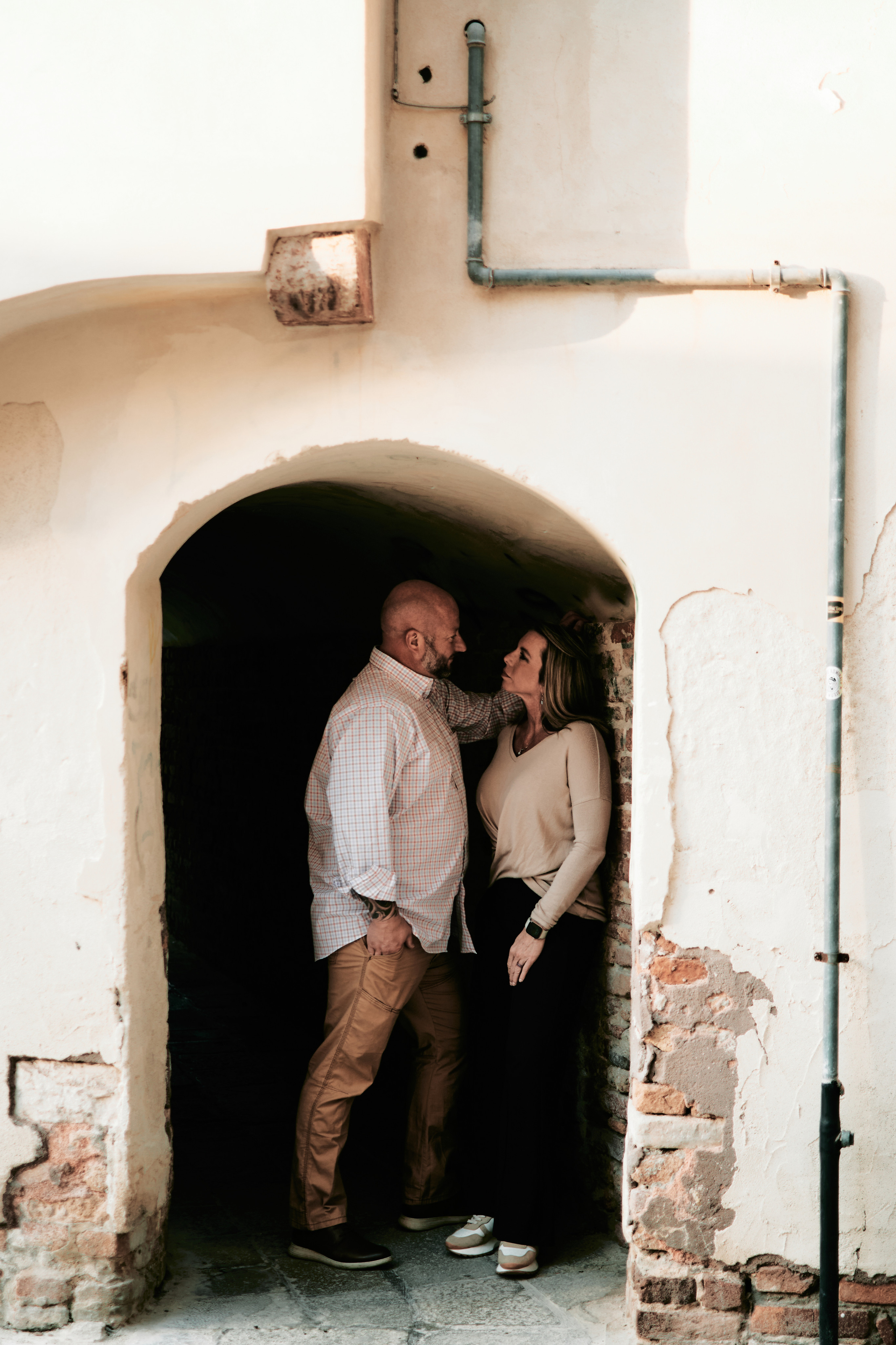 A bride and groom kiss in front of a Venetian canal with a gondola passing by in the background
