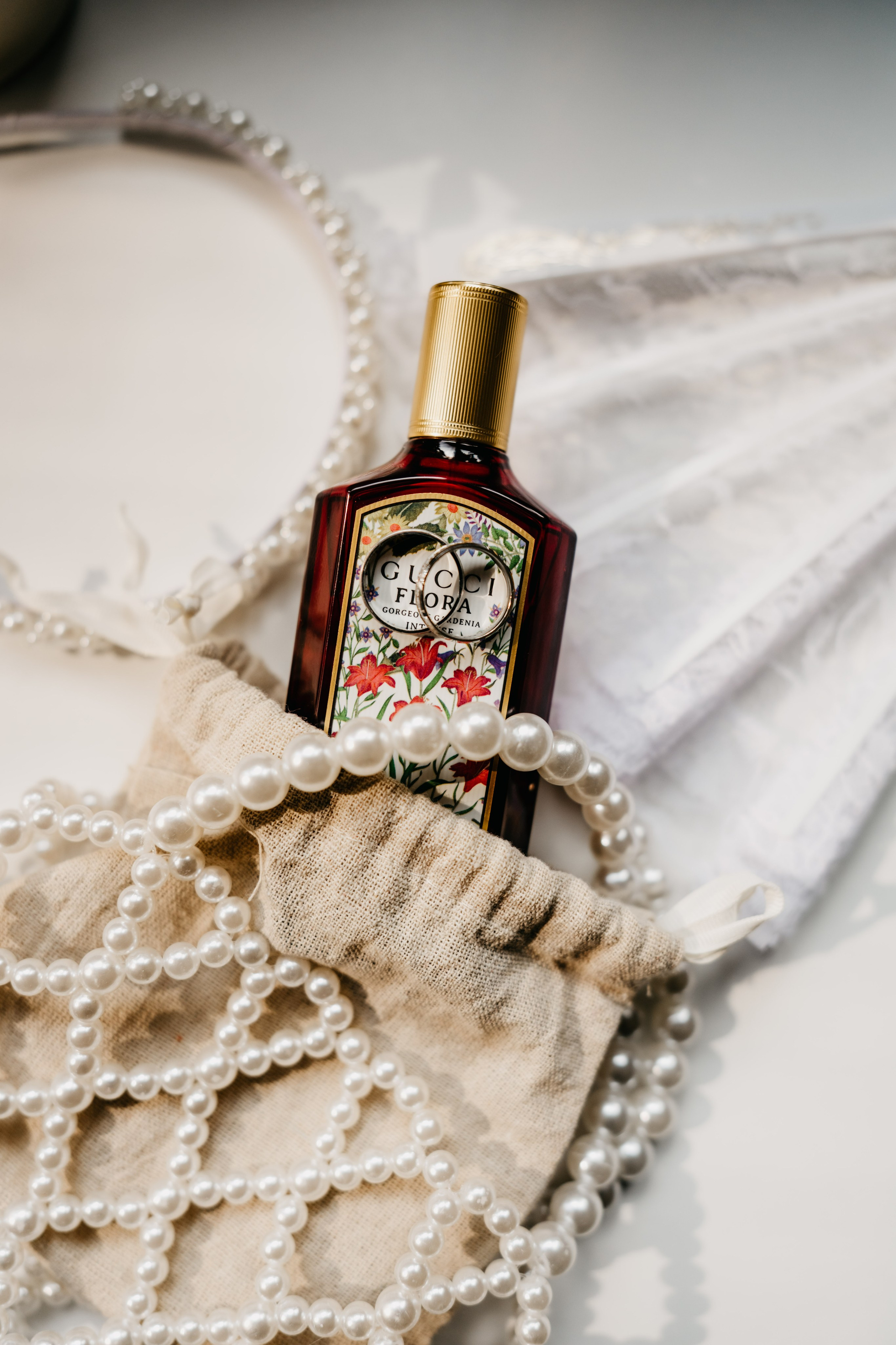 Luxury perfume, pearl handbag, and bridal accessories carefully styled during wedding preparations, creating an elegant bridal flat lay.