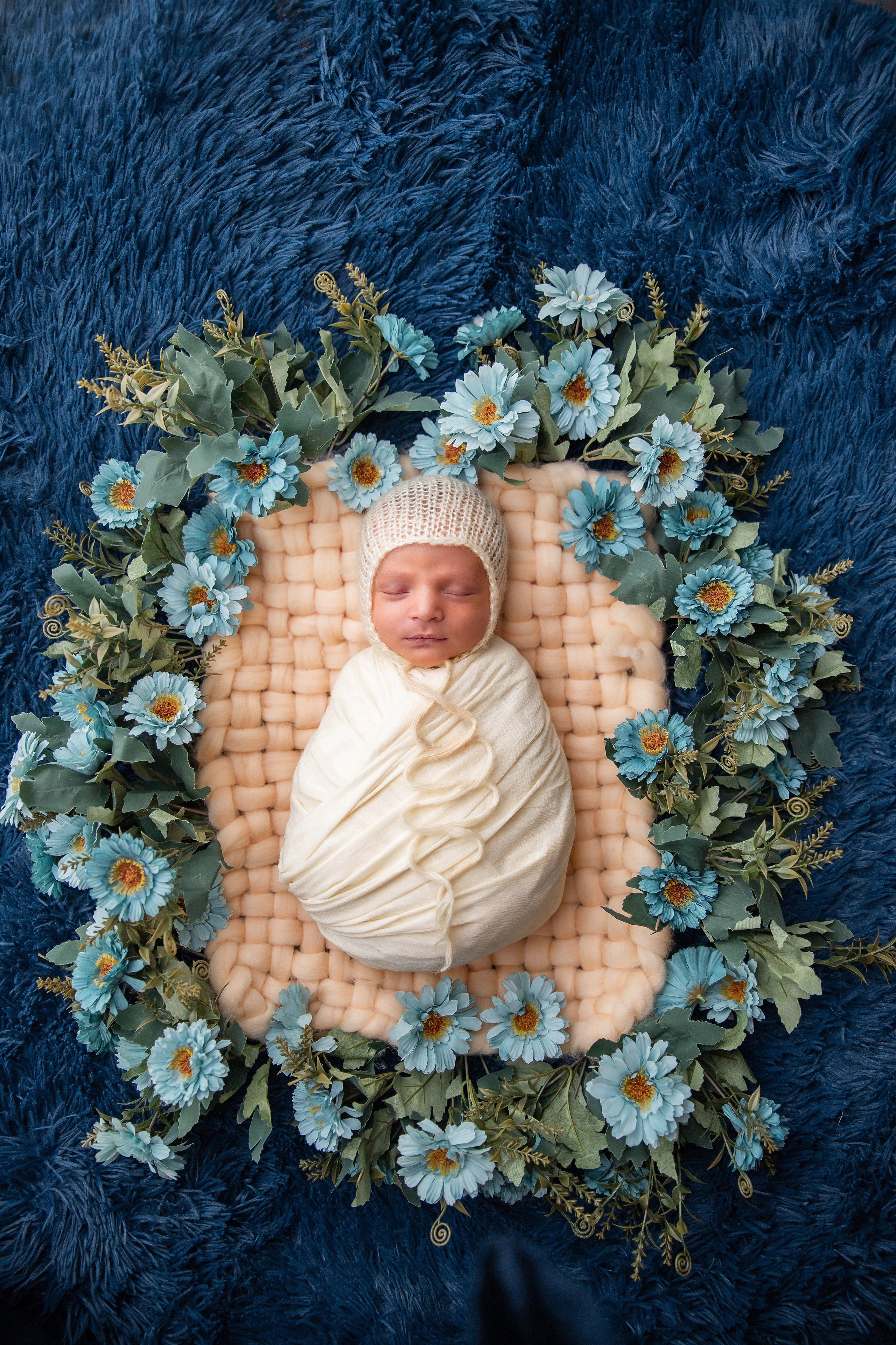 a picture of a baby that is surrounded by flowers with a blue background. baby photography. peshawar. faryal's baby photography. baby pictures. newborn. newborn picture. newborn pictures. newborn photography.