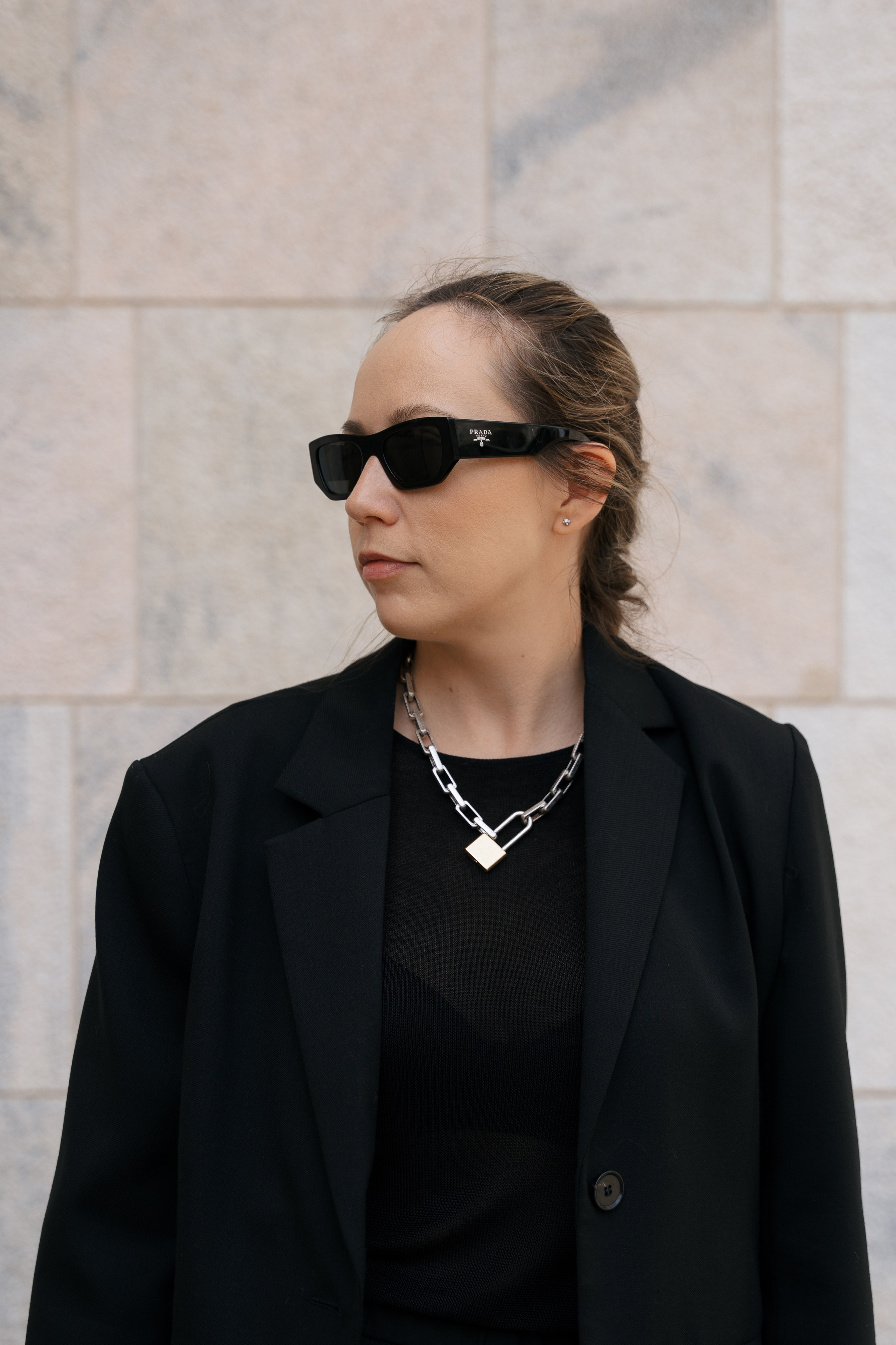 девушка в черном пиджаке позирует на фоне стены королевского дворца в Милане