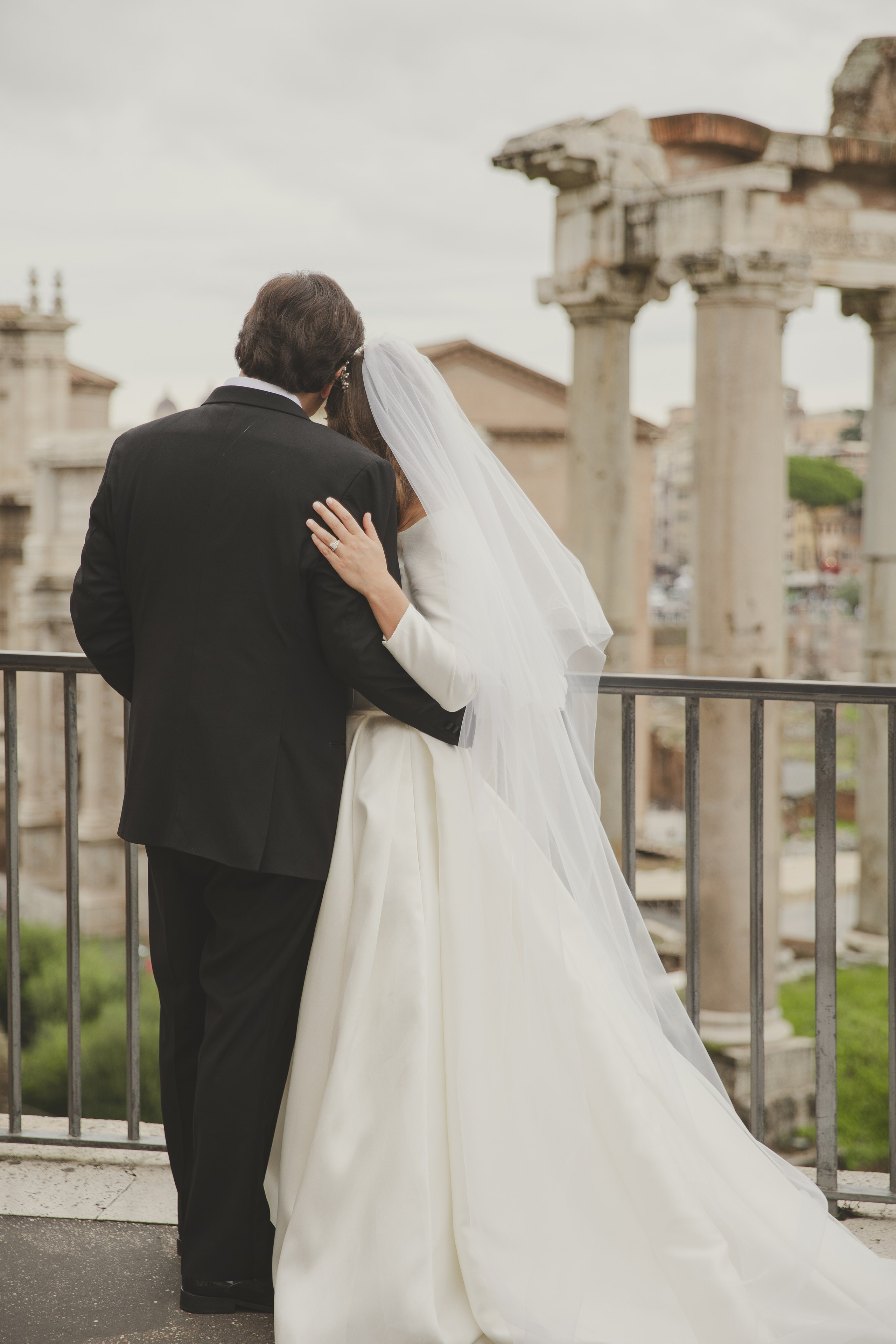 Newlyweds sharing a kiss with the Colosseum majestically in the background.