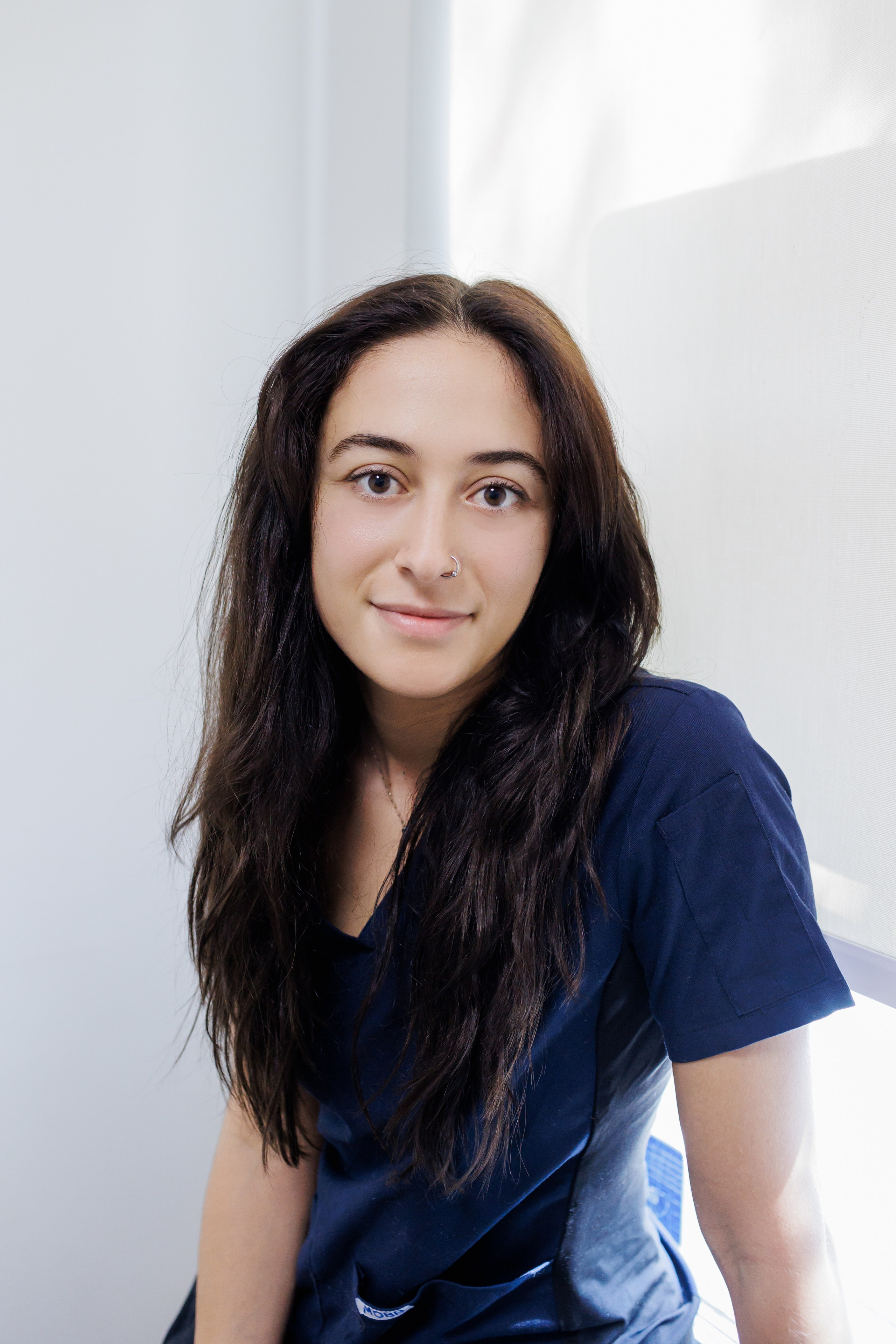 Professional headshot of a friendly female veterinary clinic employee smiling warmly in her modern clinic environment.