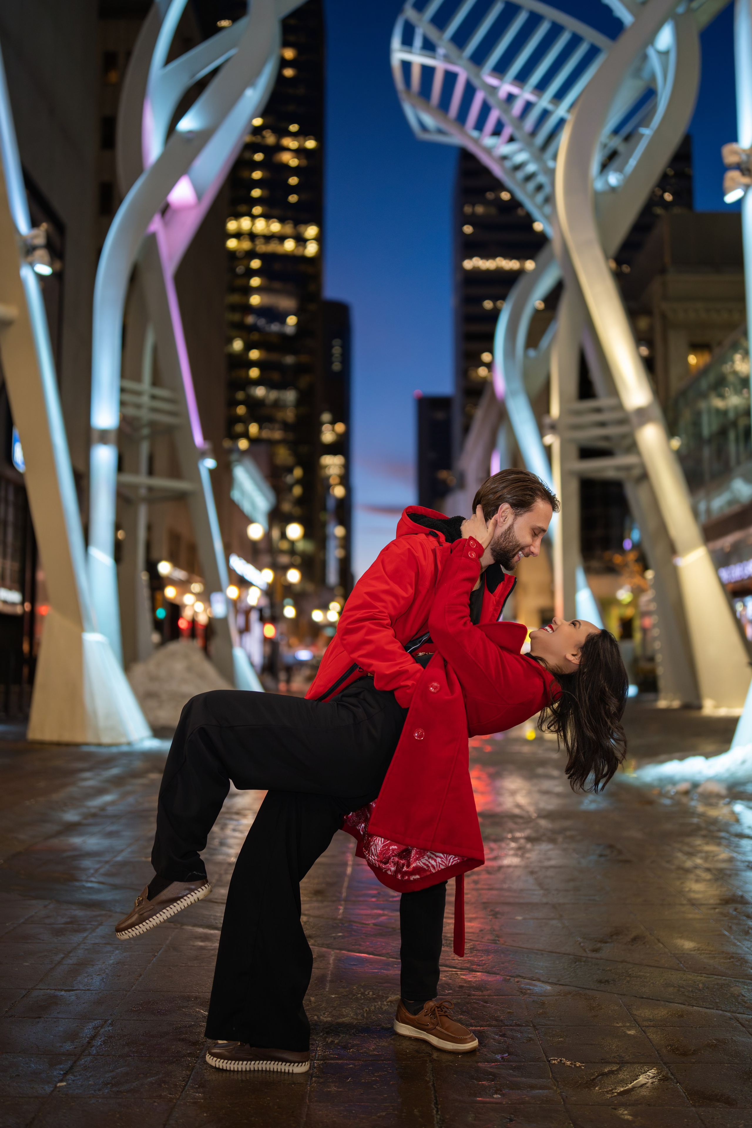 Couples mini session in downtown Calgary during winter with red winter jackets