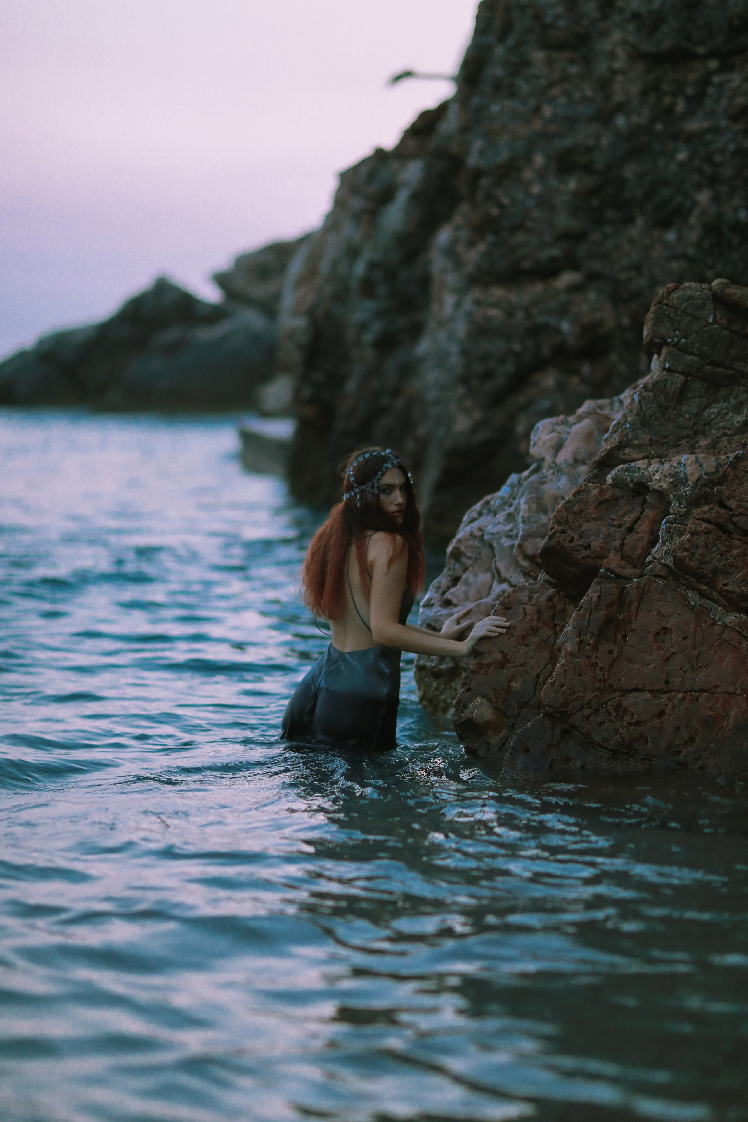Bride standing in the sea near rocky coastline in Montenegro during wedding photoshoot