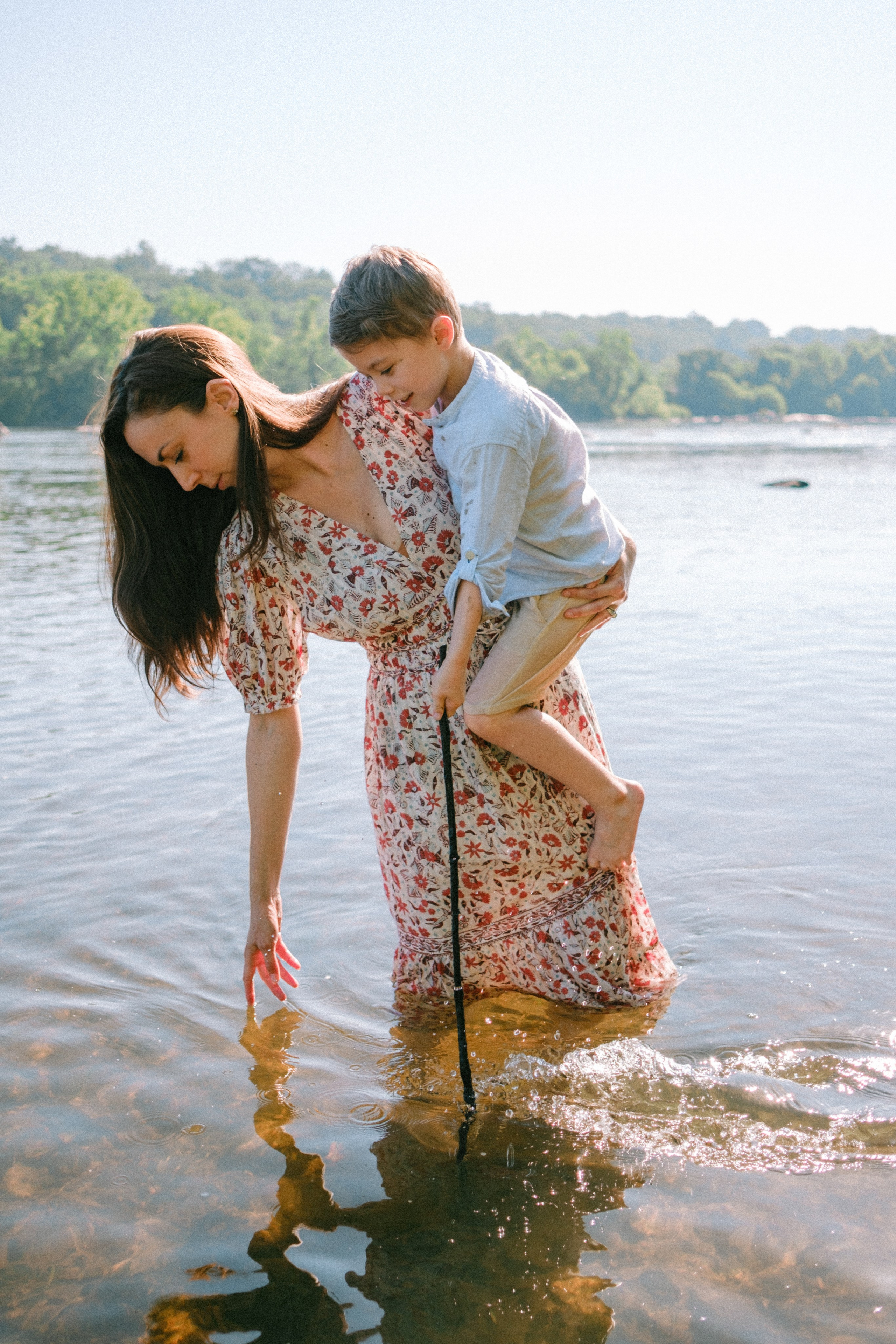 Mom holding her boy in her arms while standing in James River - documentary artistic family session at Pony Pasture in Richmond, VA