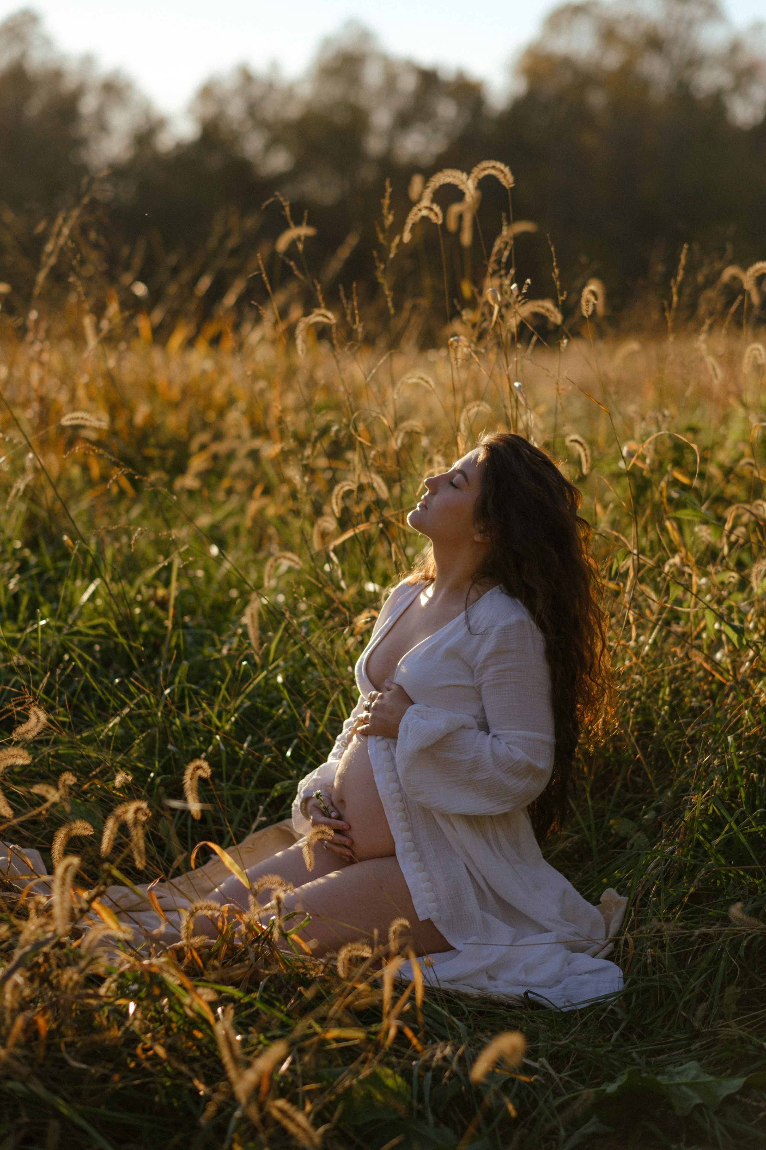 Photo of expectant mother wrapped in a flowing dress, highlighted by natural light Richmond, VA