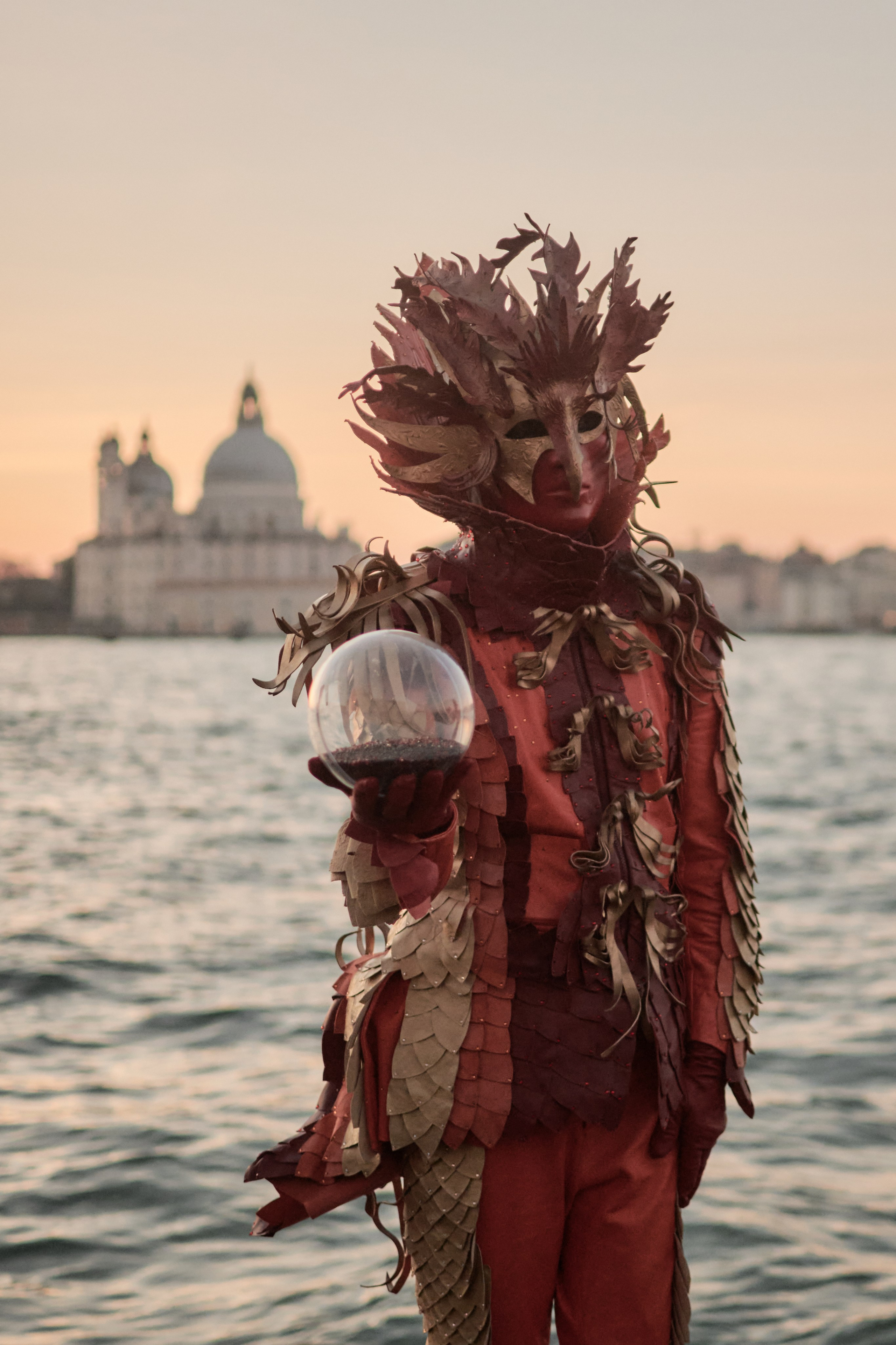 A performer wearing a mask and costume walking on stilts during the carnival parade.