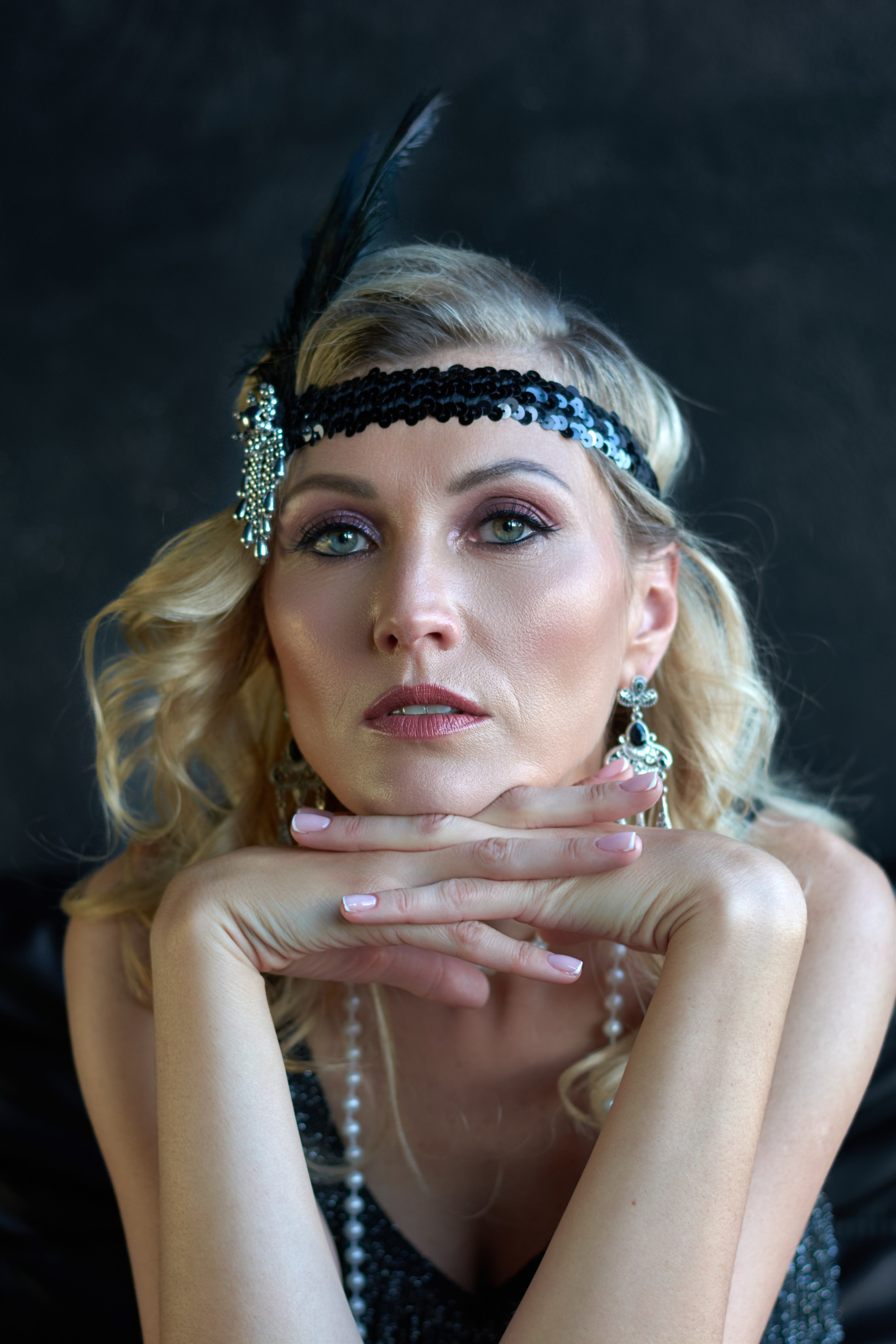 Portrait of a woman as a flapper, hands folded under her chin, direct gaze