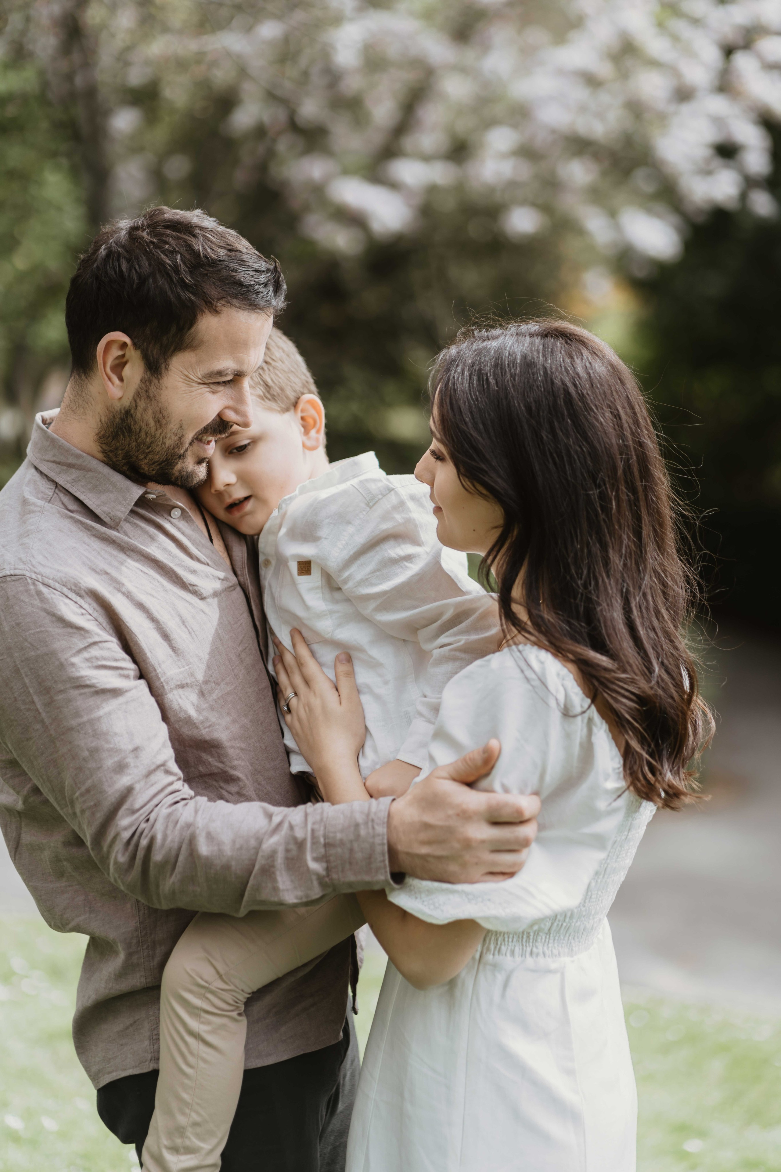 Parents holding child during outdoor family photoshoot in London with soft natural styling.