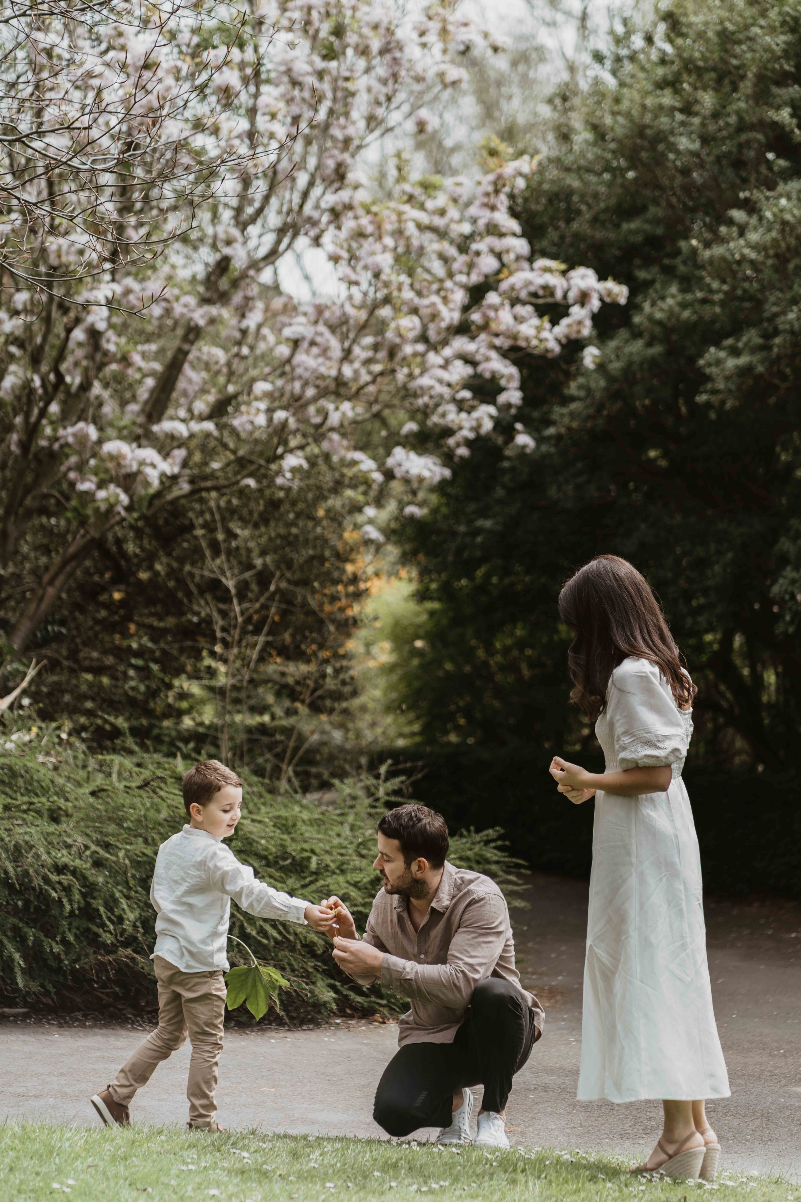 Family walking in blooming London garden during spring photoshoot with elegant neutral clothing.