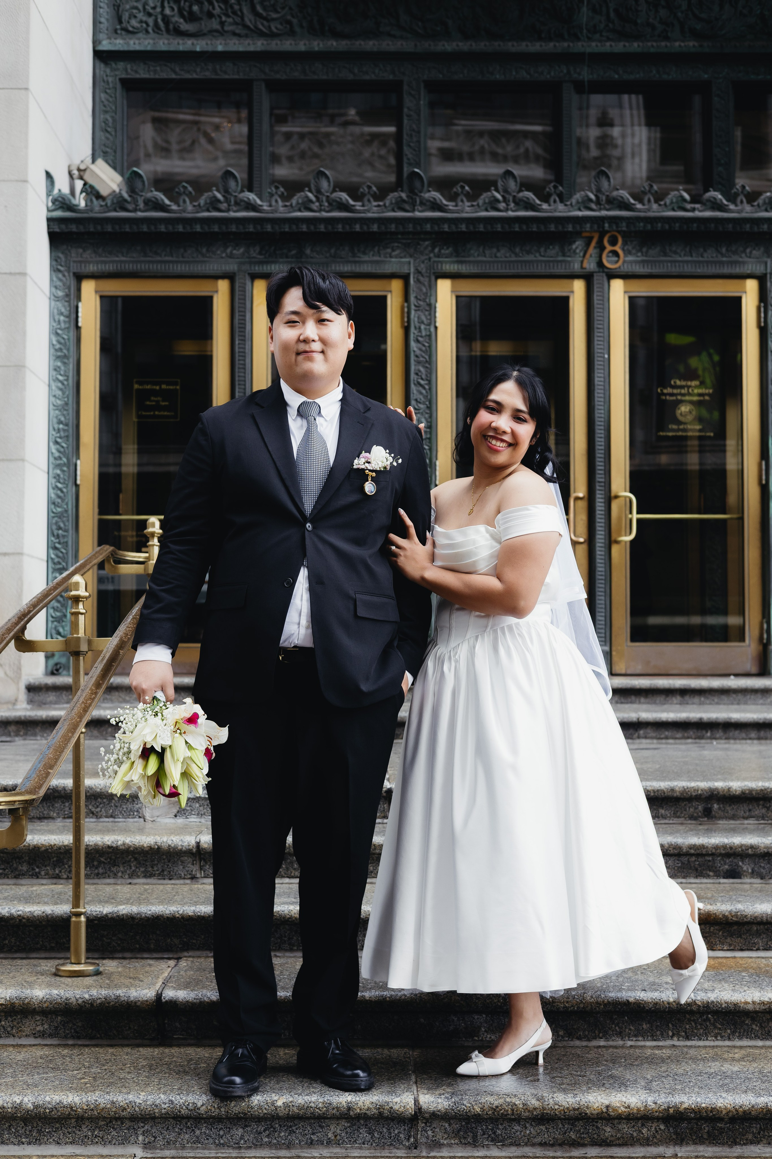 Wide shot of couple standing on the steps of the Chicago Cultural Center