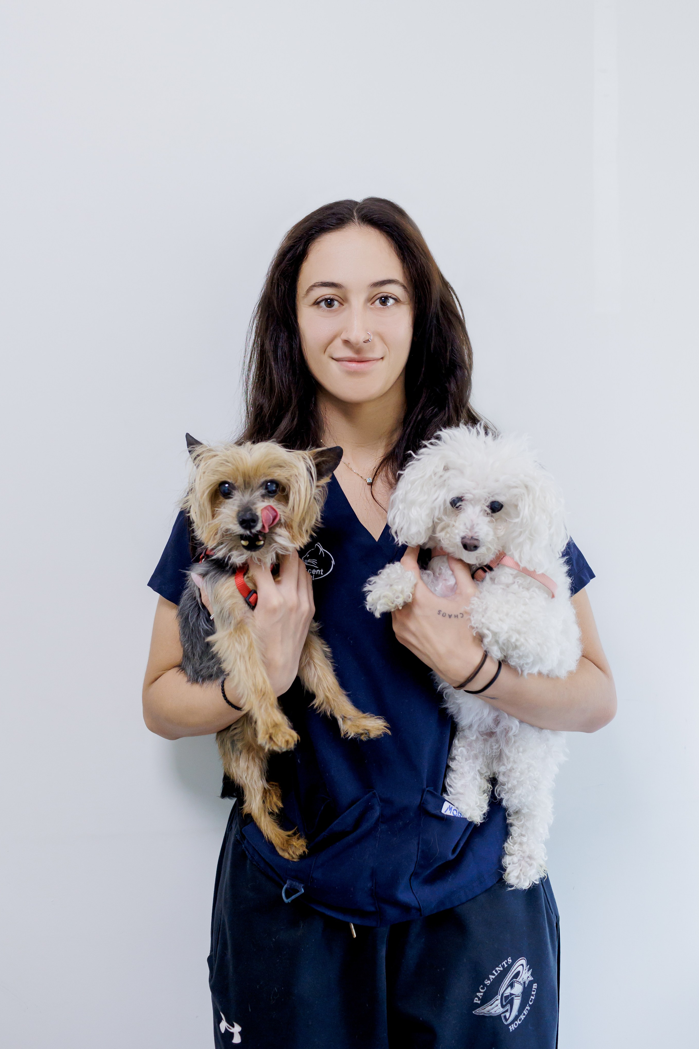 Professional headshot of a friendly female veterinary clinic owner smiling warmly in her modern clinic environment.
