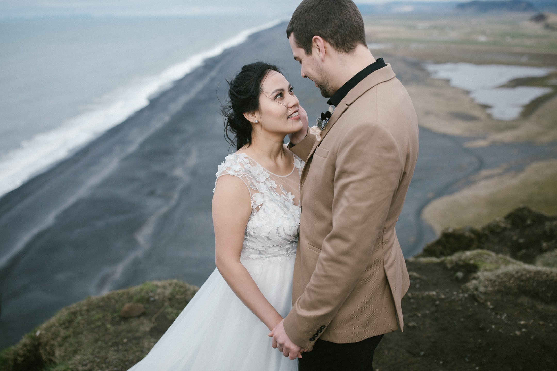 Couple embracing with ocean and coastline in background