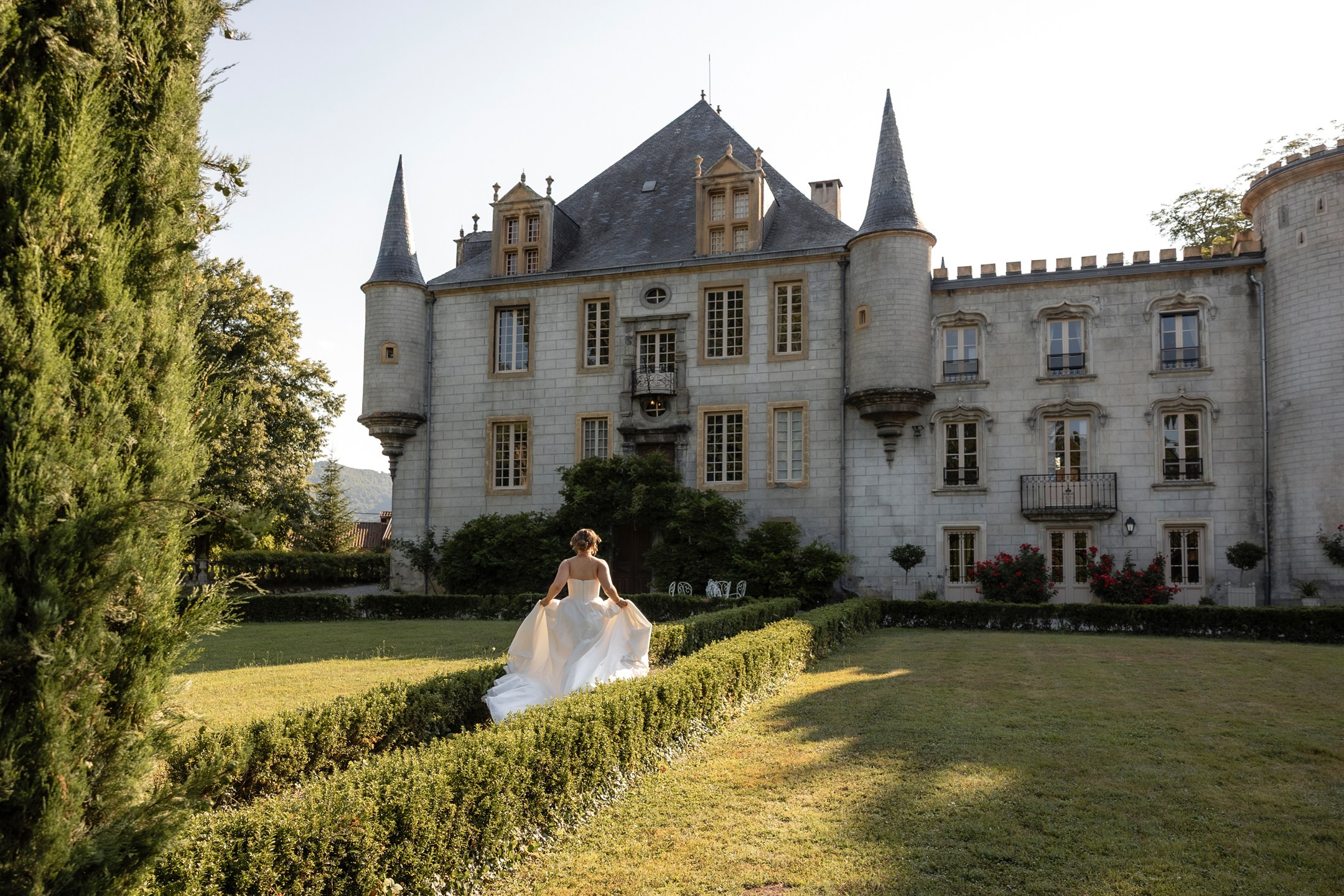 Elegant château wedding venue in Southwest France with bride walking through garden