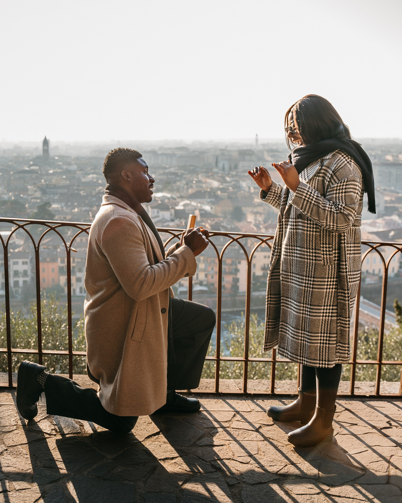 Marriage proposal in Verona with man kneeling at sunset overlooking the city.
