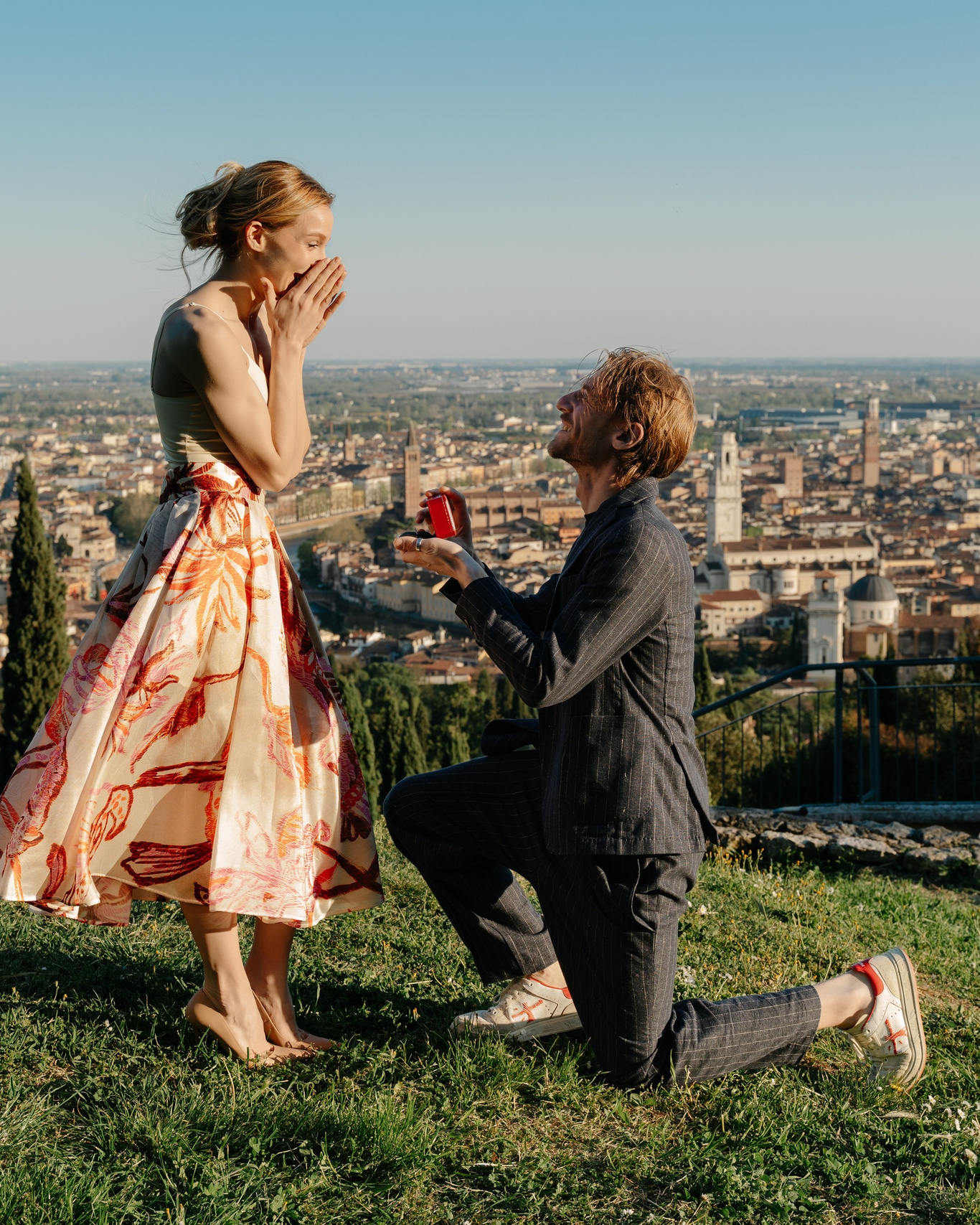 Marriage proposal in Verona with man kneeling at sunset overlooking the city.