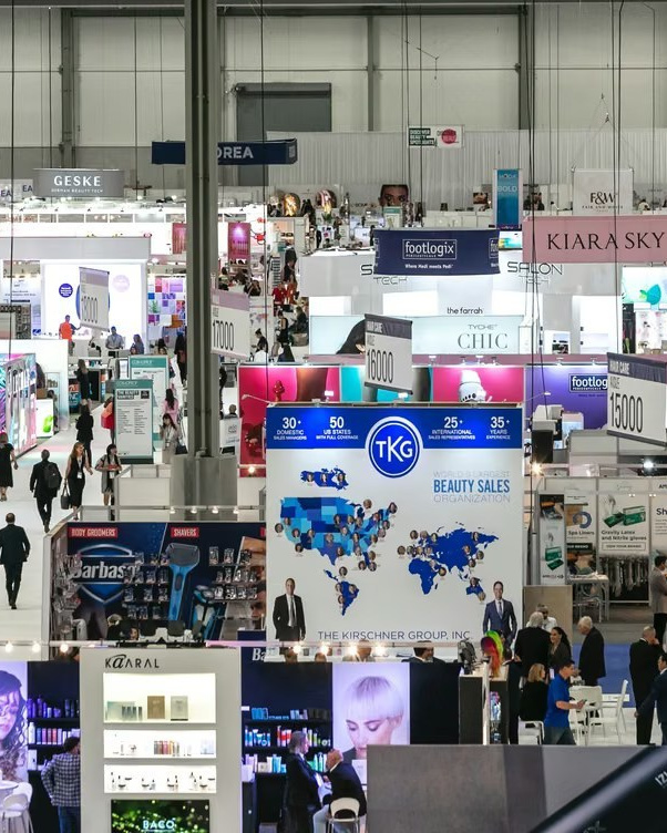 Trade exhibition floor with branded stands and visitors, viewed from above