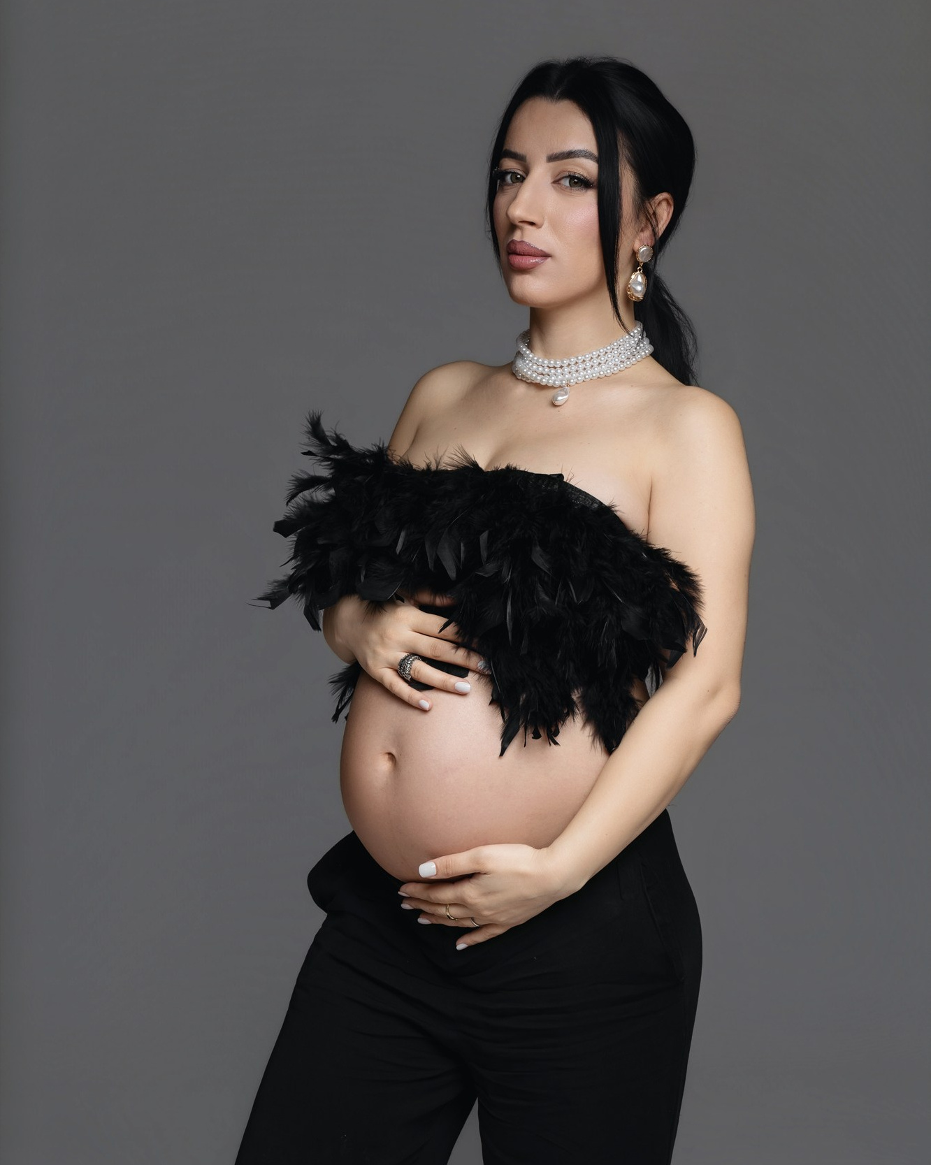 Ritratto elegante di una futura mamma in abito nero durante un servizio fotografico gravidanza in studio a Padova.