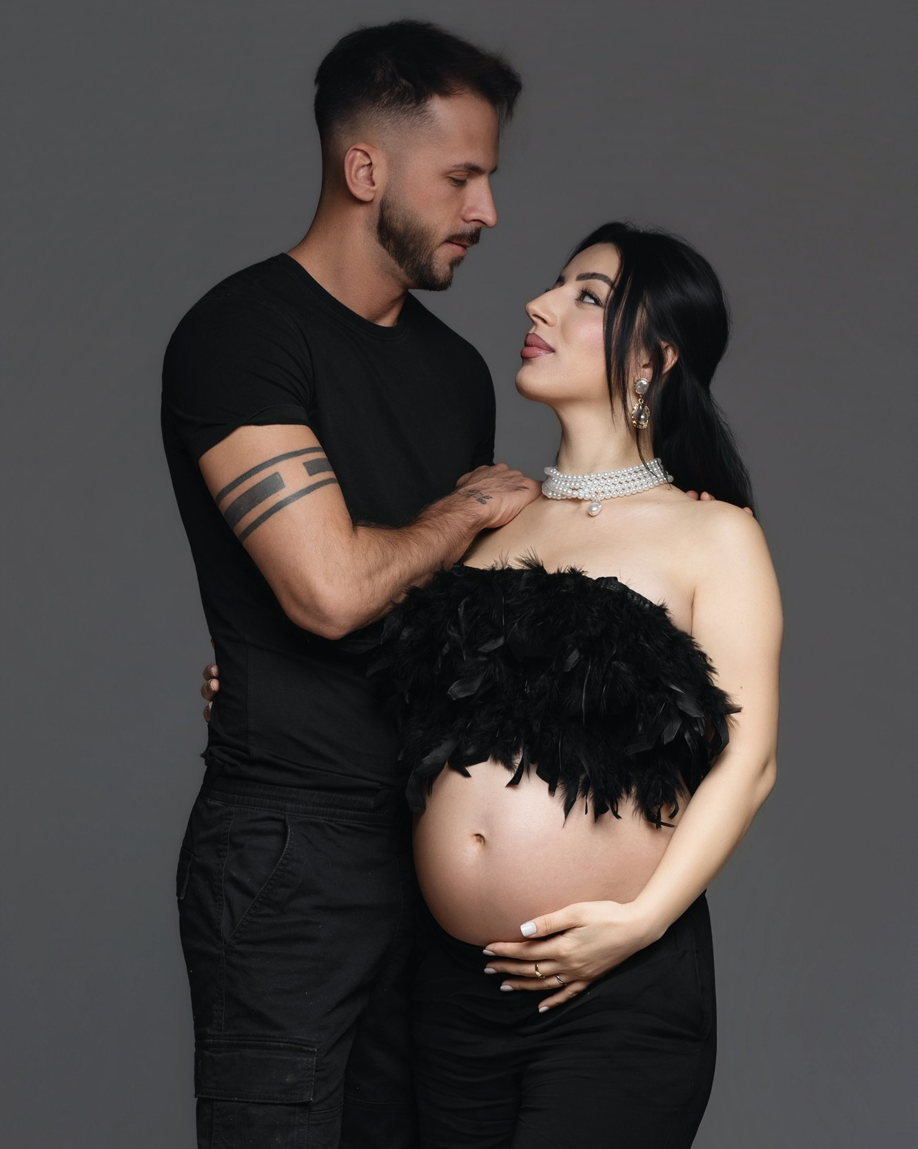 Coppia in dolce attesa durante un servizio fotografico di gravidanza in studio a Padova, in un abbraccio intimo.