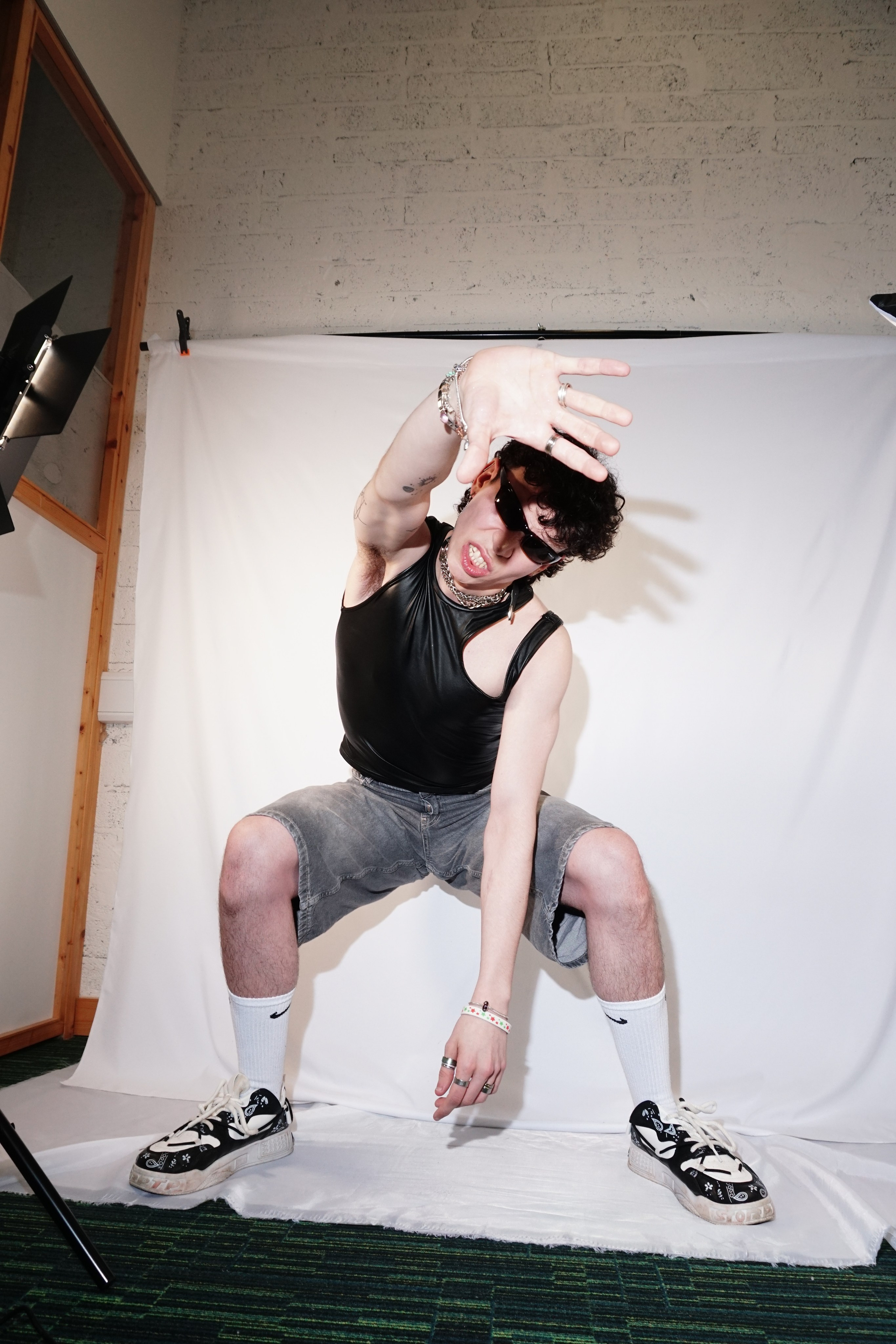 Portrait of a male model in a leather top posing expressively in a creative studio setup with white backdrop and flash lighting — AMELPOMENEM PHOTO, Wexford.