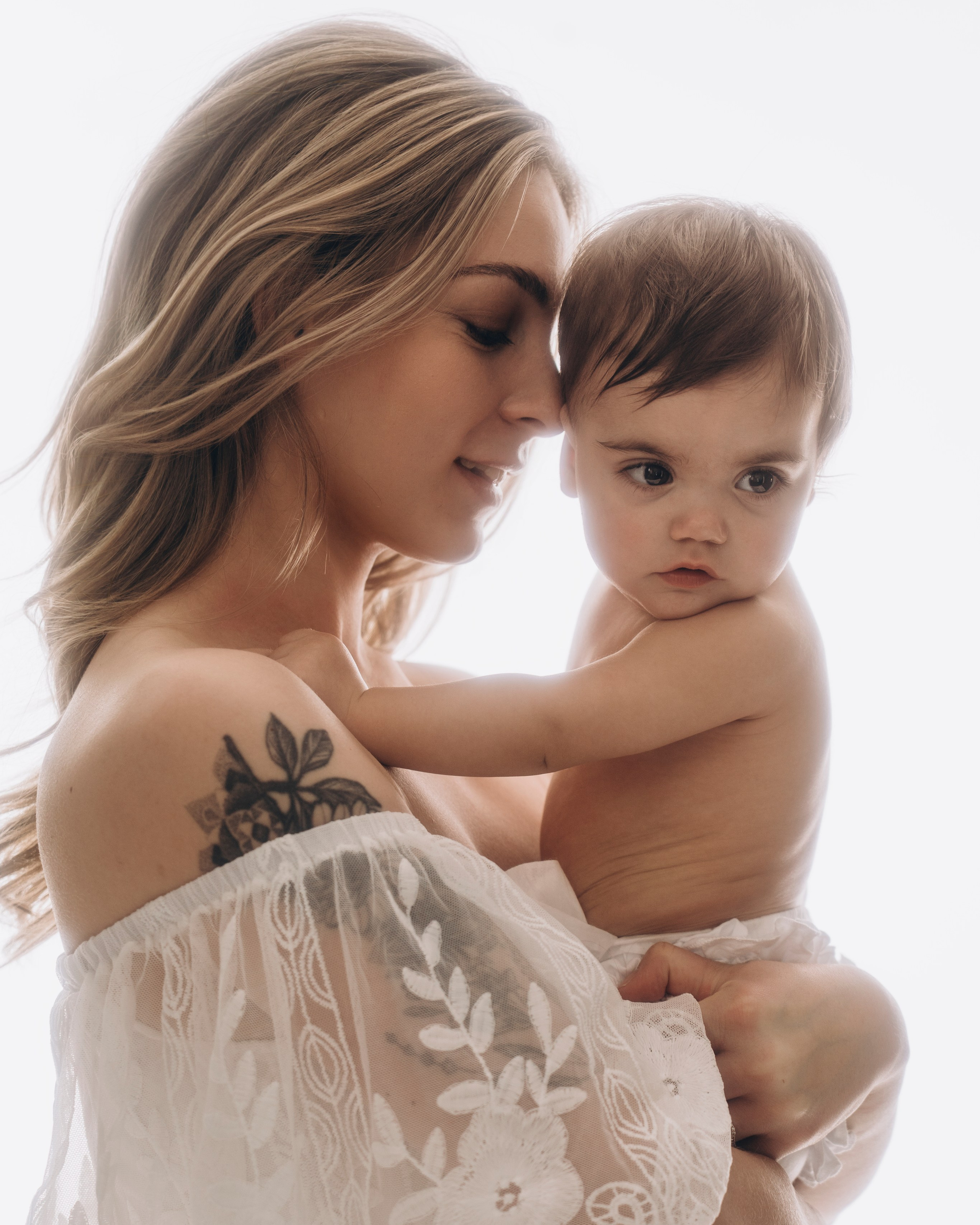 Connecticut motherhood portrait, mother holding toddler in white lace gown, soft and light studio.