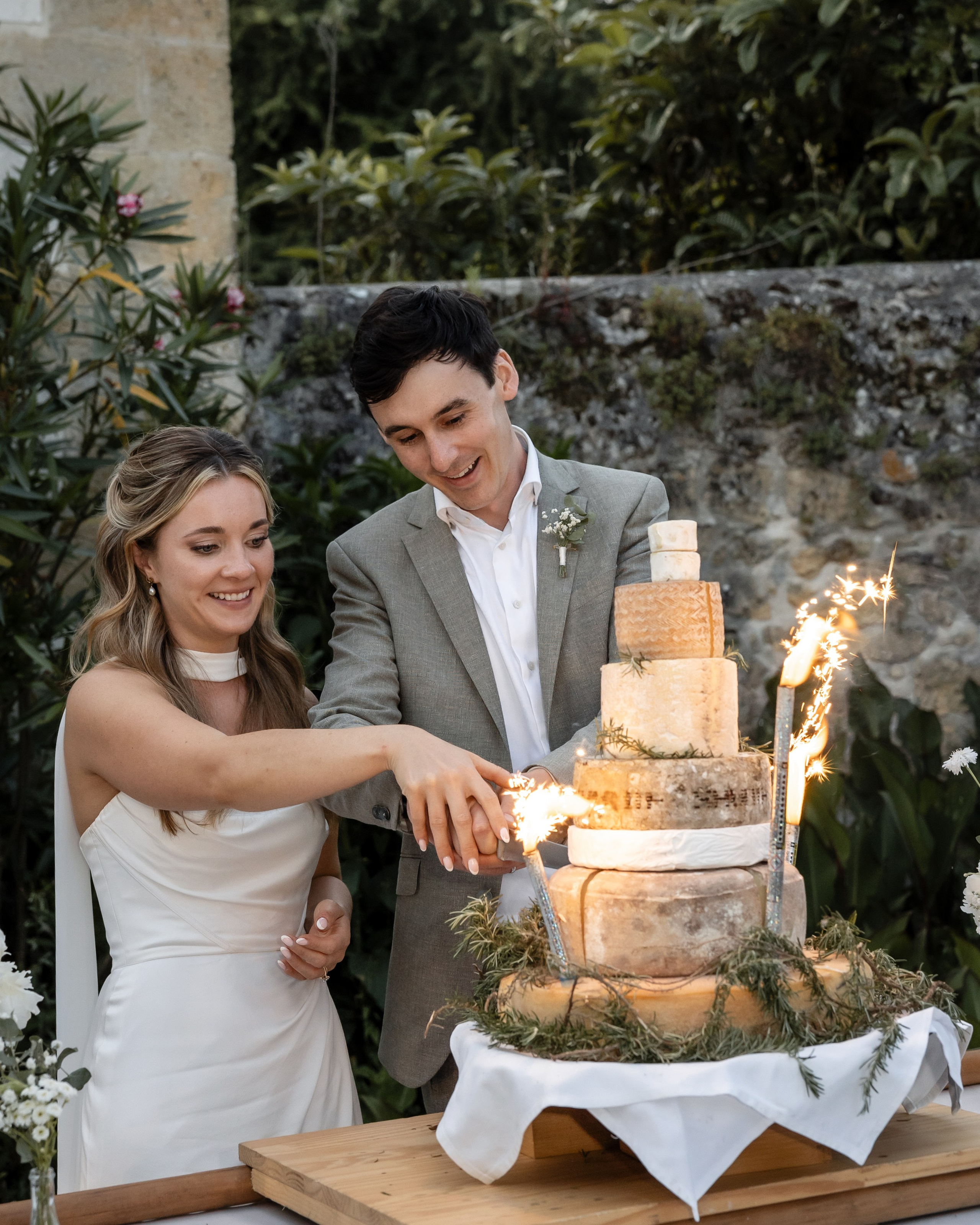 Bride and groom cutting a traditional French cheese wedding cake with sparklers during their wedding reception at Château Sentout in Southwest France.