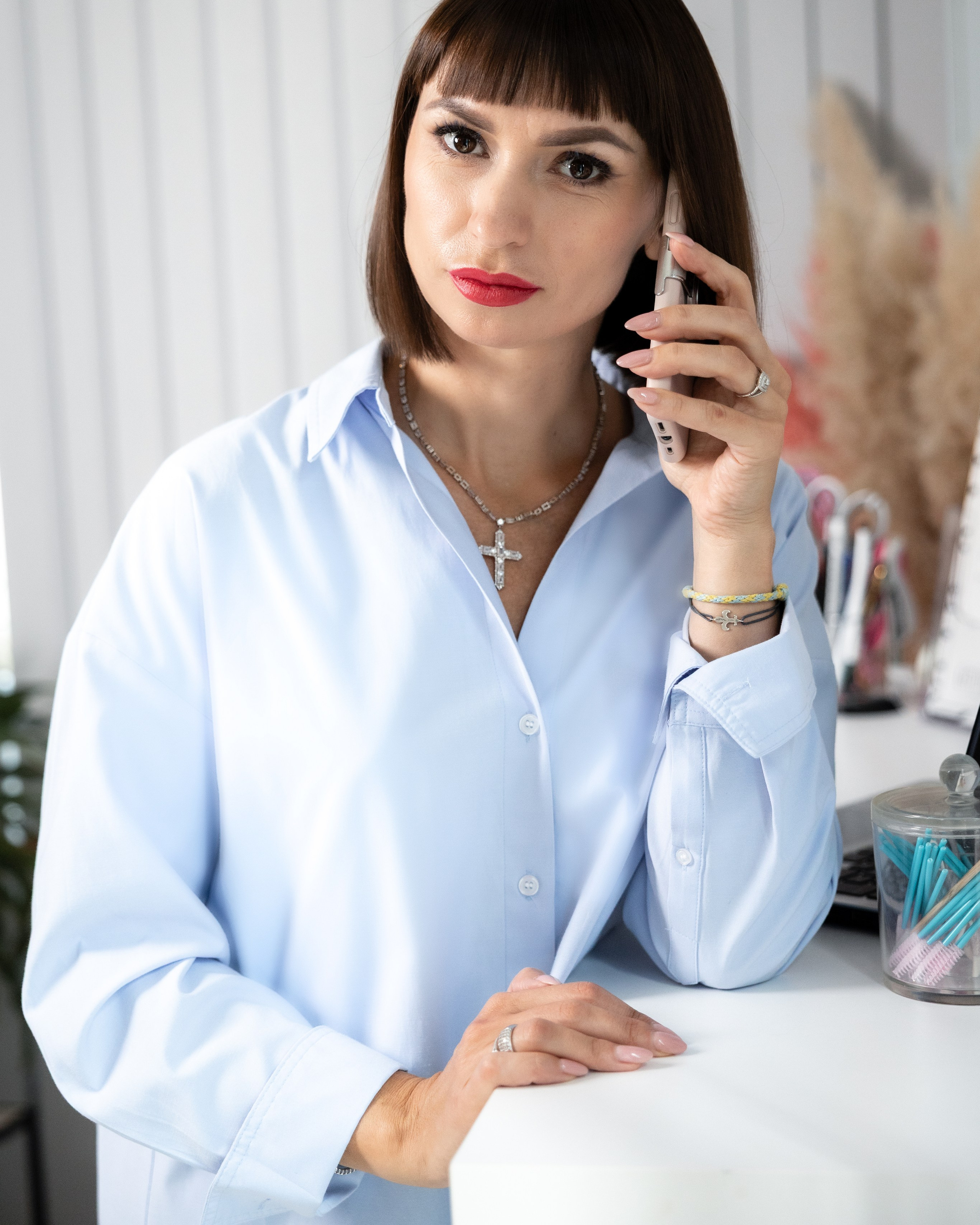Brunette in light shirt on a phone call, hand to ear, personal brand session in Toulouse
