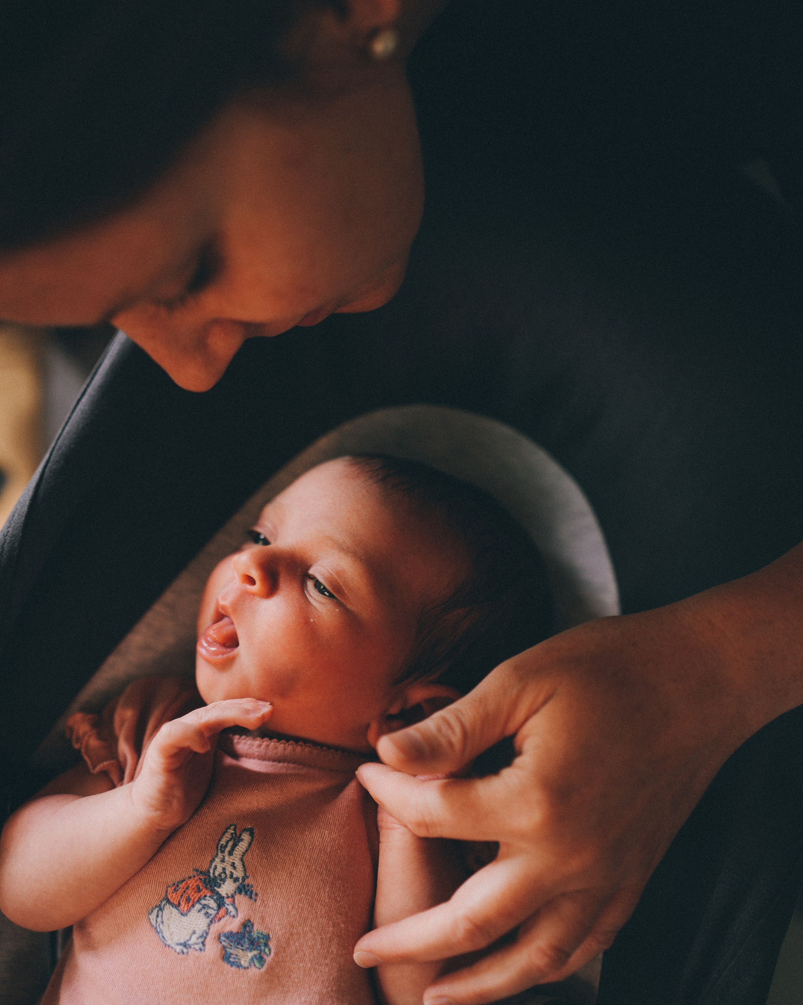 Mother holding newborn baby by the window during a soft natural light newborn photography session in Solihull